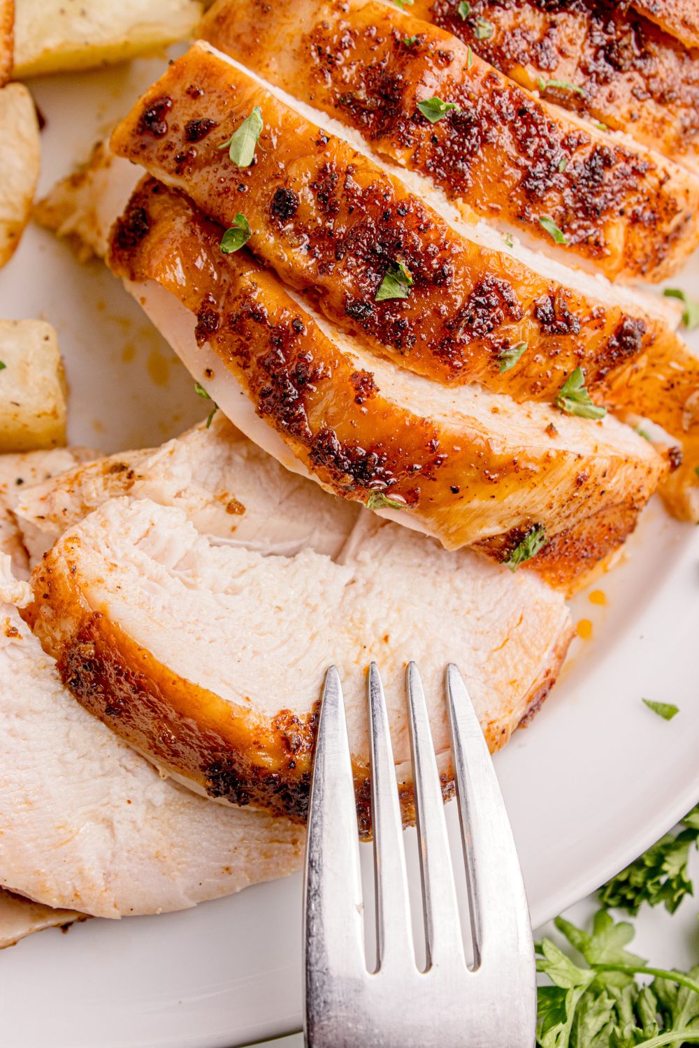 sliced chicken on table with a fork sitting on top of meat