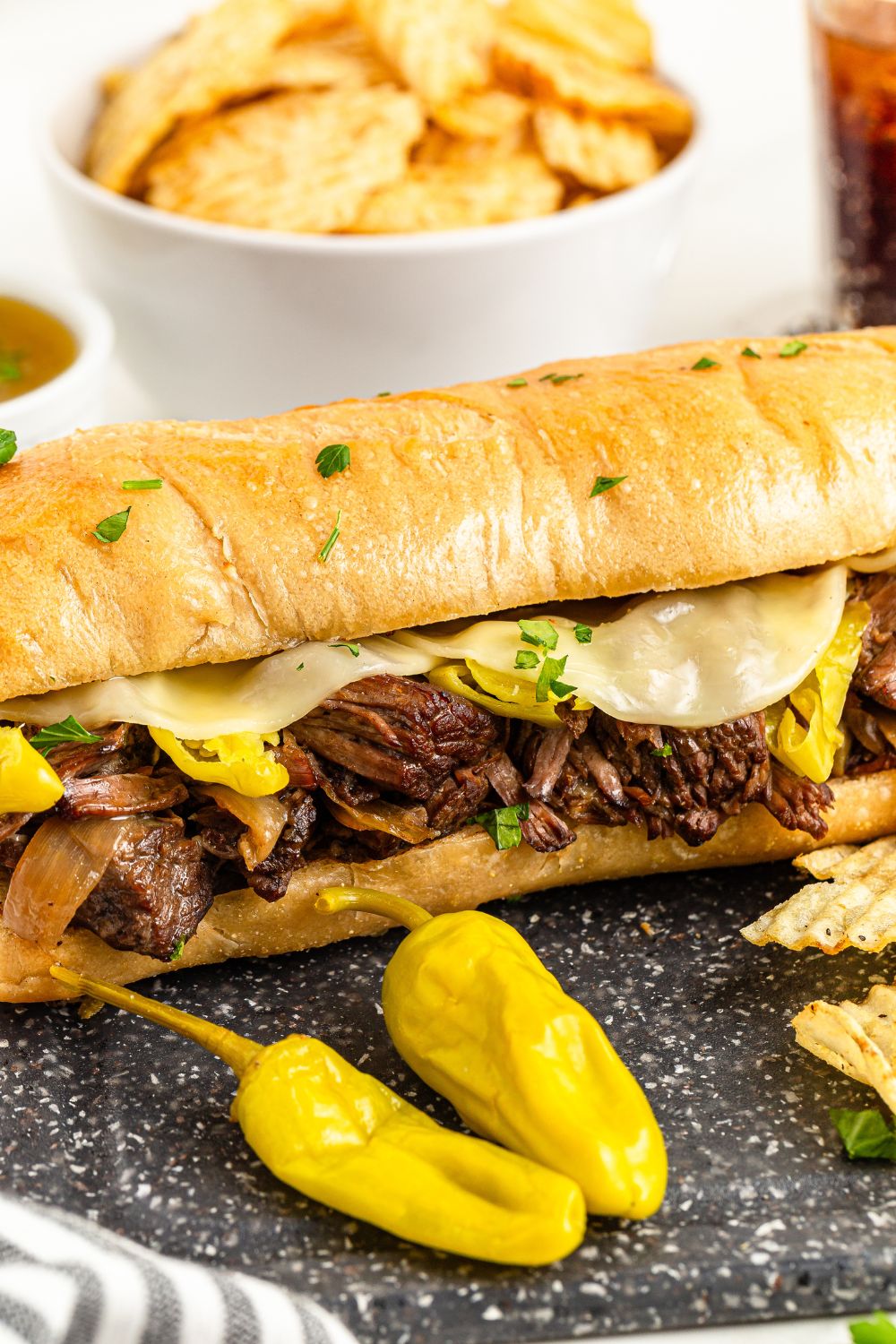 Mississippi Pot Roast Sandwich on table with peppers in front of it 