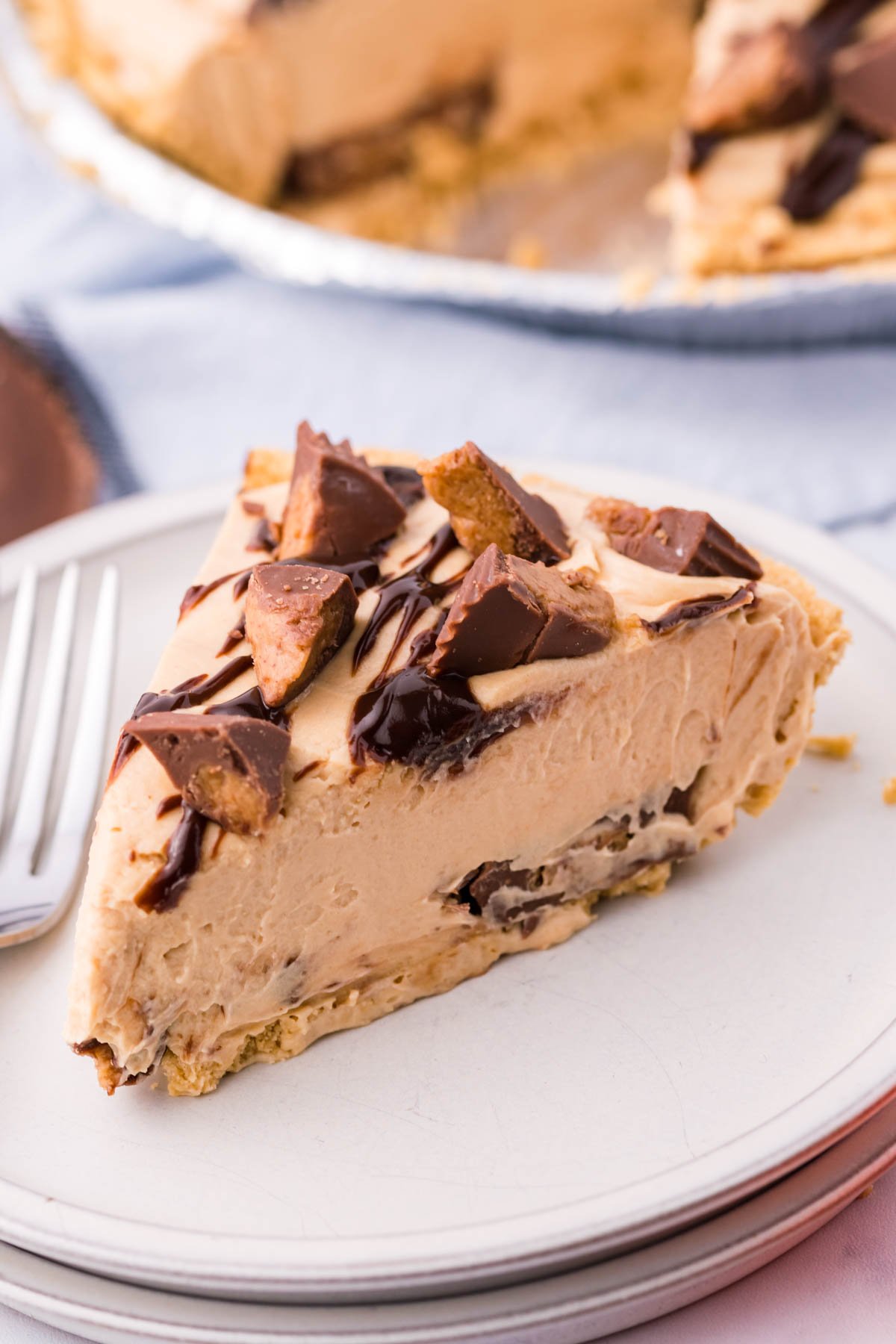 A slice of no bake peanut butter cup pie on a white plate with a silver fork.