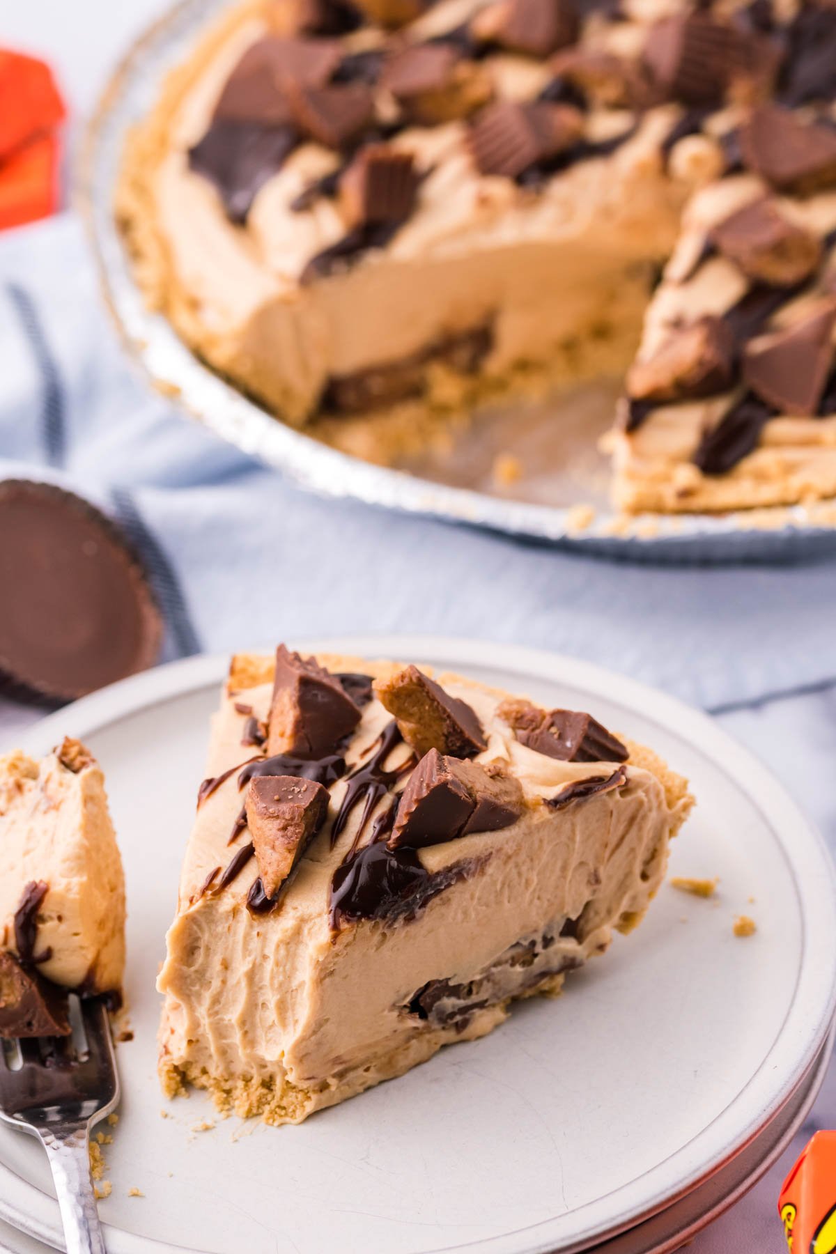 Reeses no bake pie slice on a white plate with the whole pie in the background