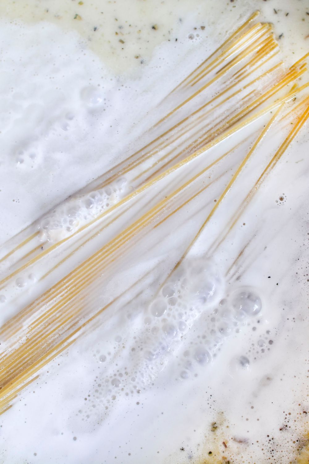 dry pasta tossed in skillet with a creamy garlic sauce 