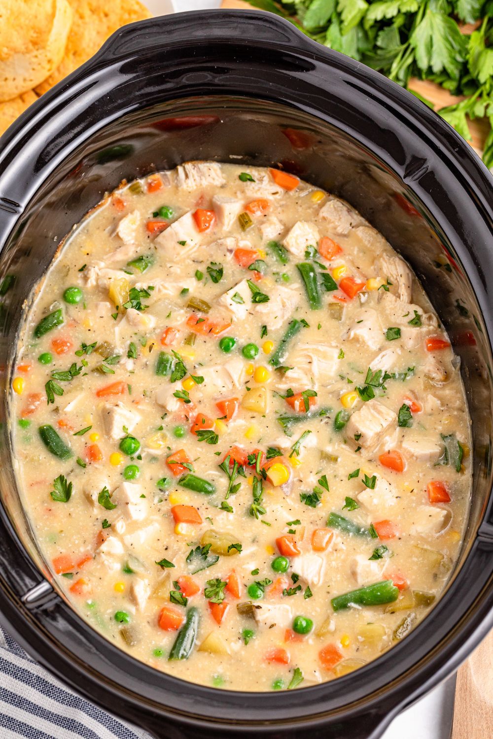 Slow Cooker Chicken Pot Pie in a slow cooker sitting on table with a towel on side 