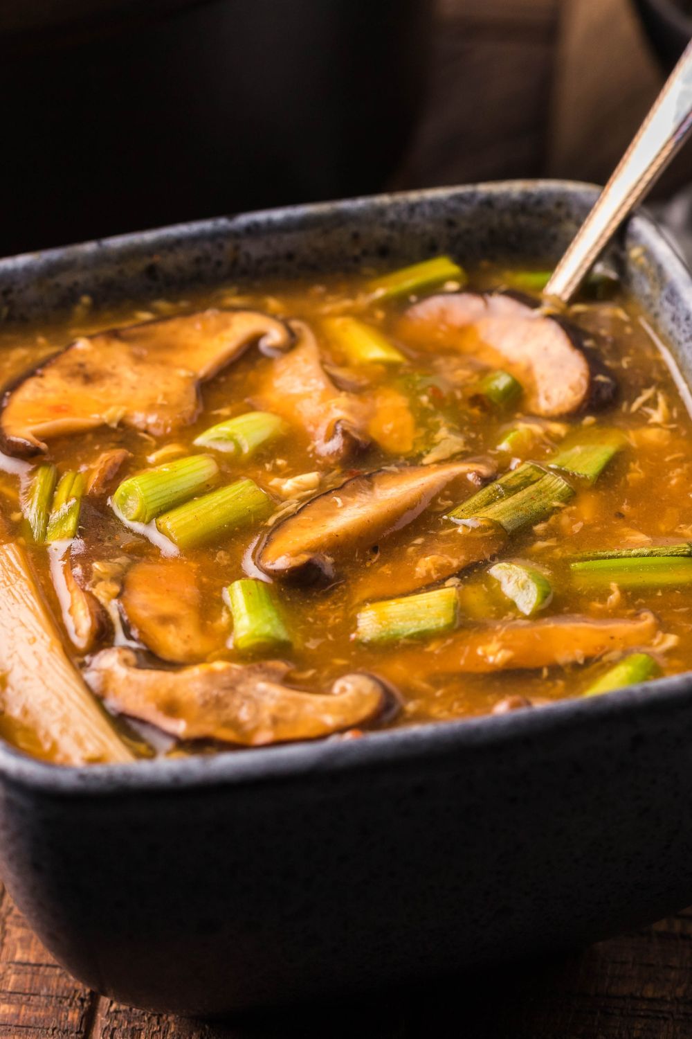 PF Changs Hot And Sour Soup in a square bowl with a spoon in bowl on table 