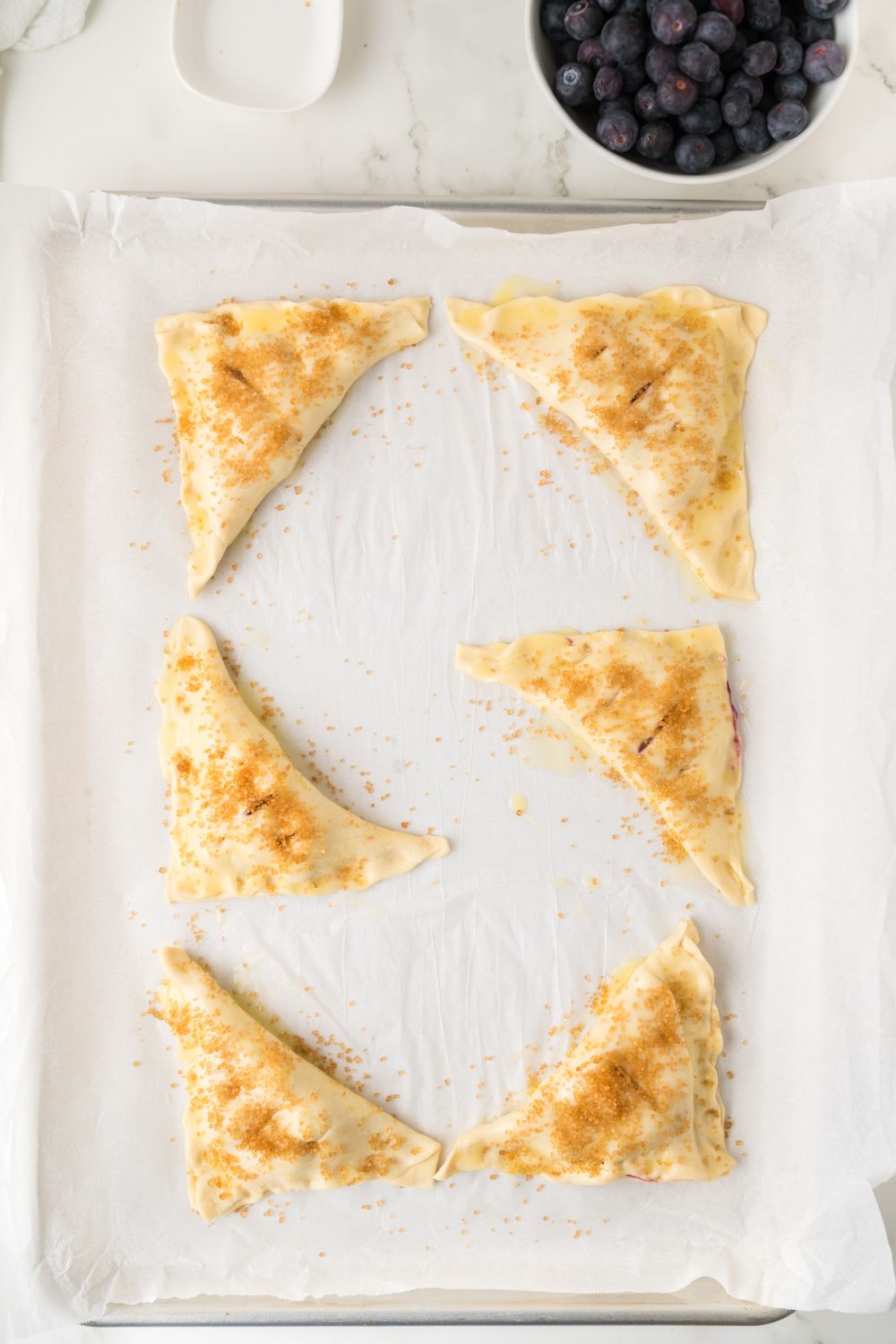 Blueberry Turnovers on tray brushed with butter 