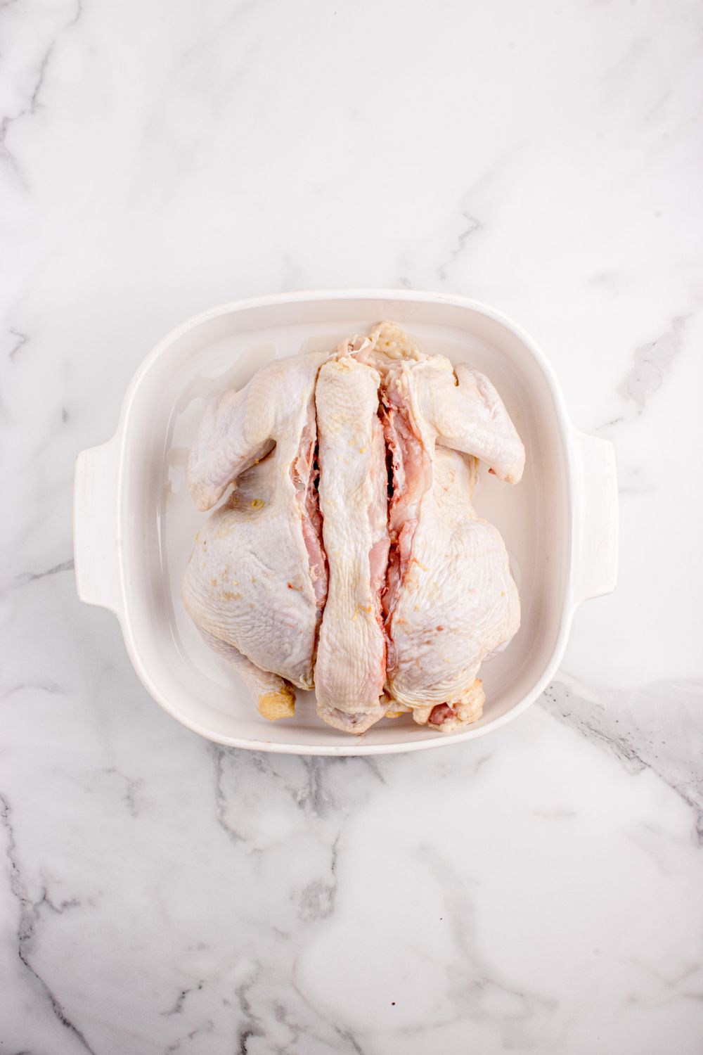 raw chicken in container with cuts down the center