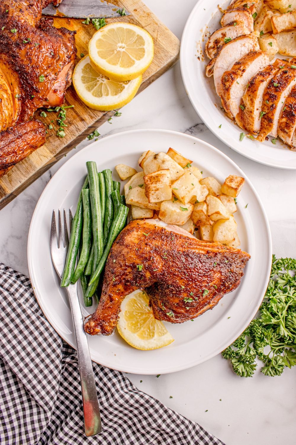smoked chicken on plate with veggies and a tray with more chicken around it 