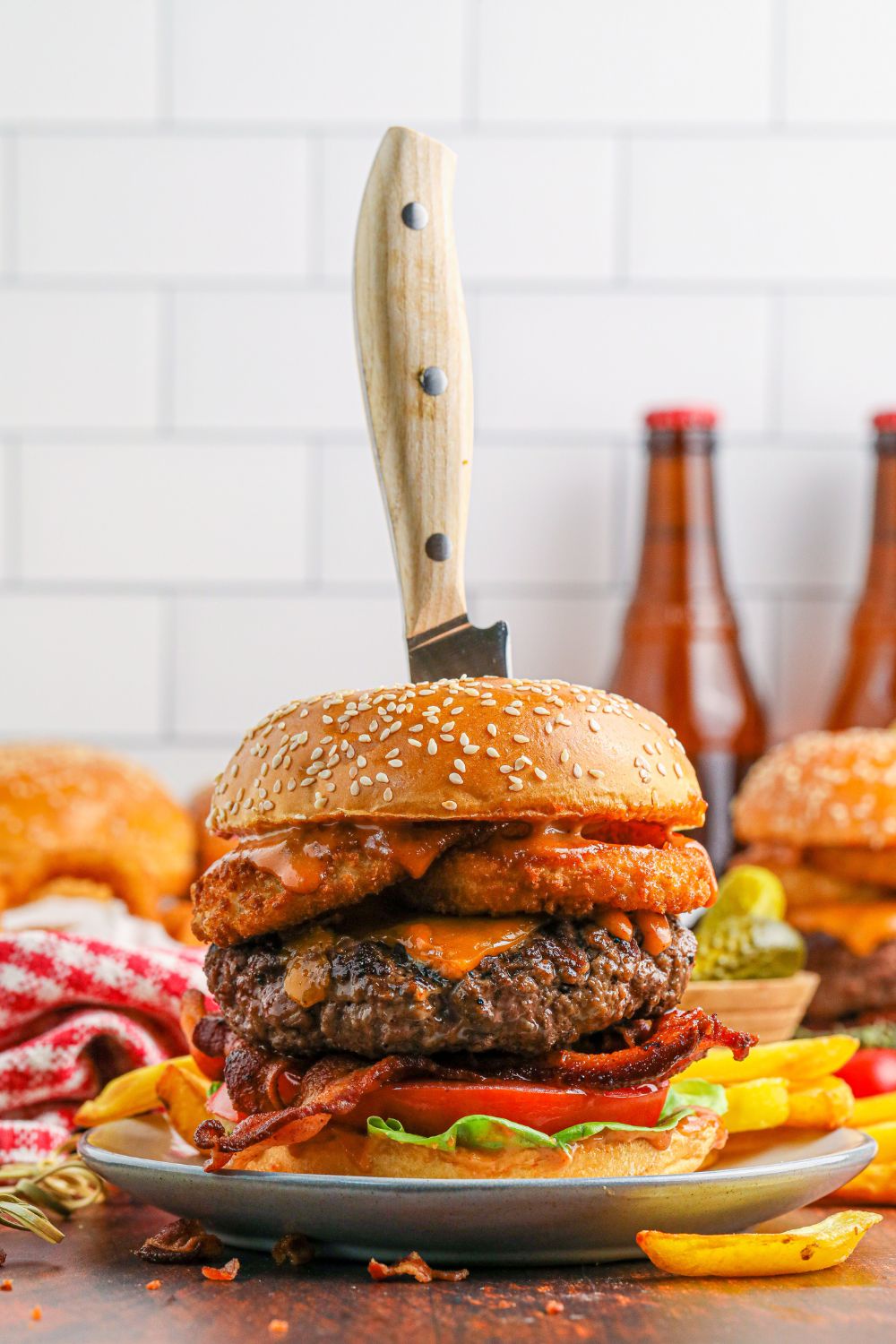 Cowboy Burgers on plates with a knife stabbed in center to show how thick the burgers are 