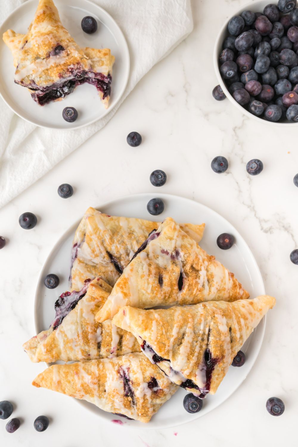 overhead look of a plate full of Blueberry Turnovers with some berries to the side 