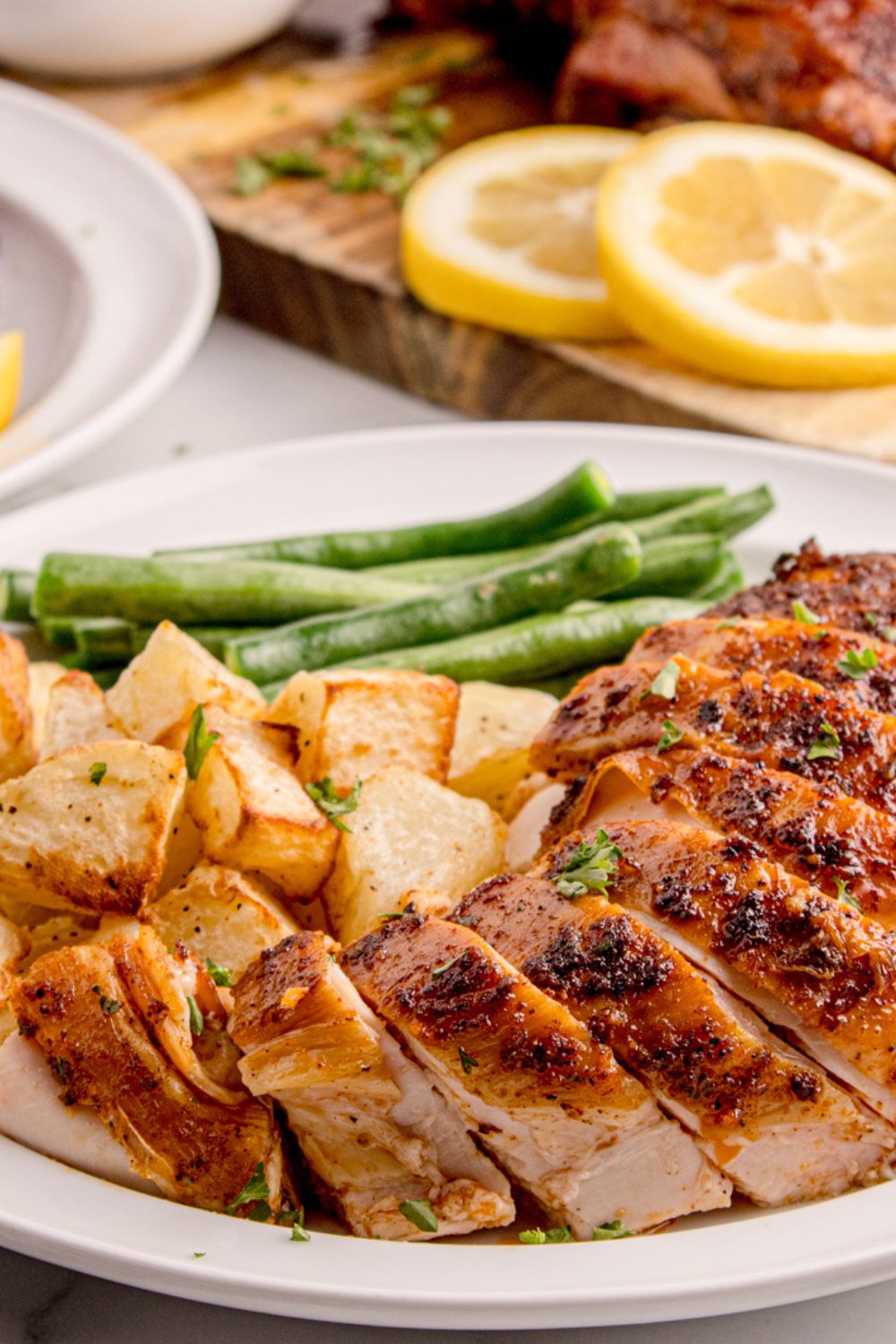 Smoked sliced Chicken on plate with potatoes and green beans on side 