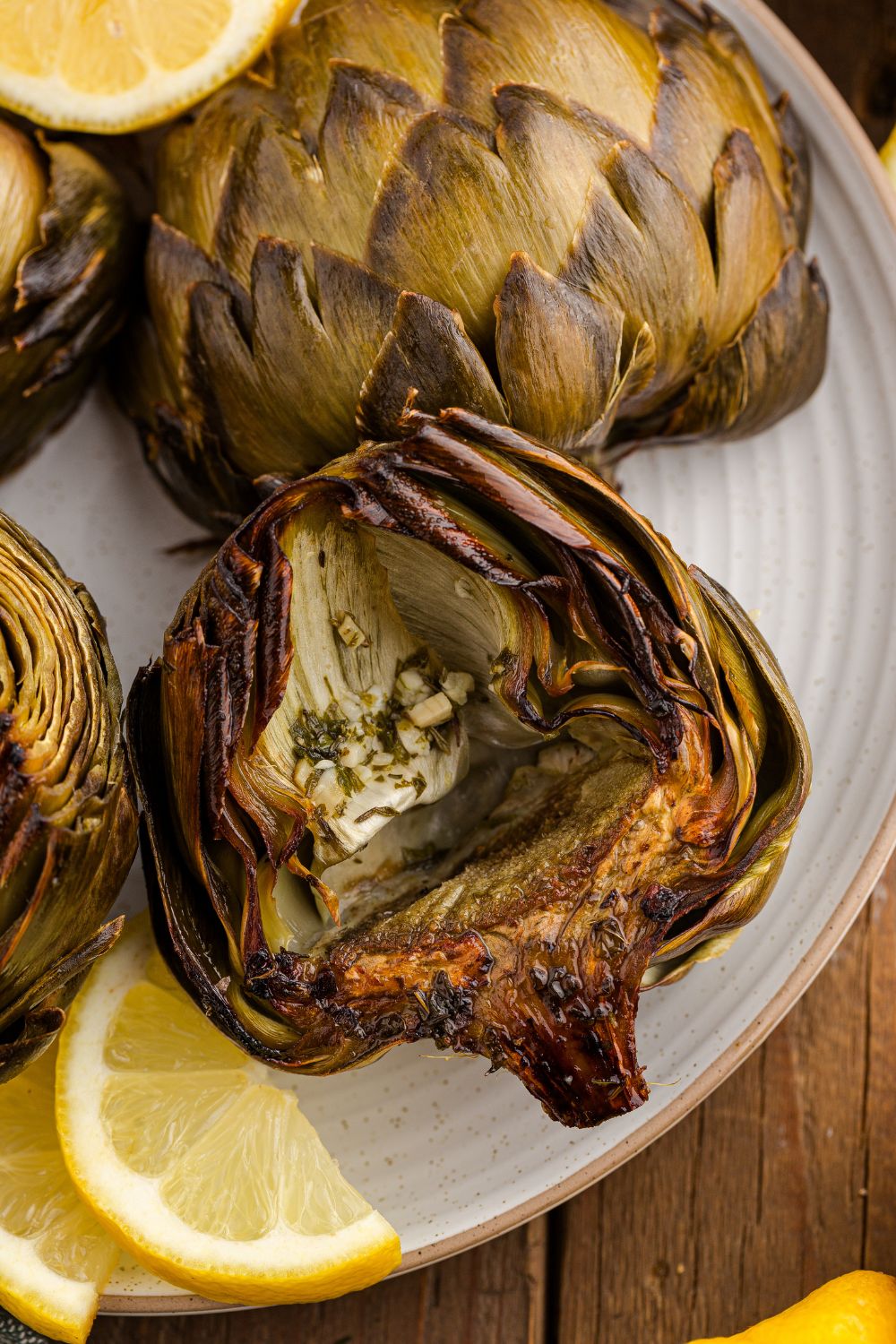 Oven Roasted Artichokes on table with lemon wedges on the side 