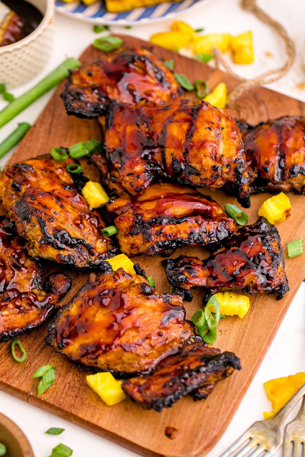 table with a platter of Huli Huli Chicken on it and garnished with green onions 