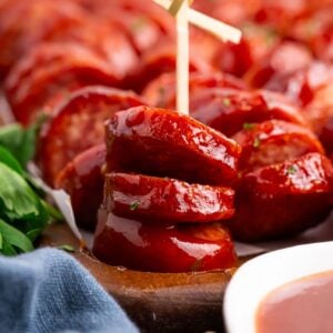 BBQ Hasselback Smoked Sausages on table with one with a toothpick in it