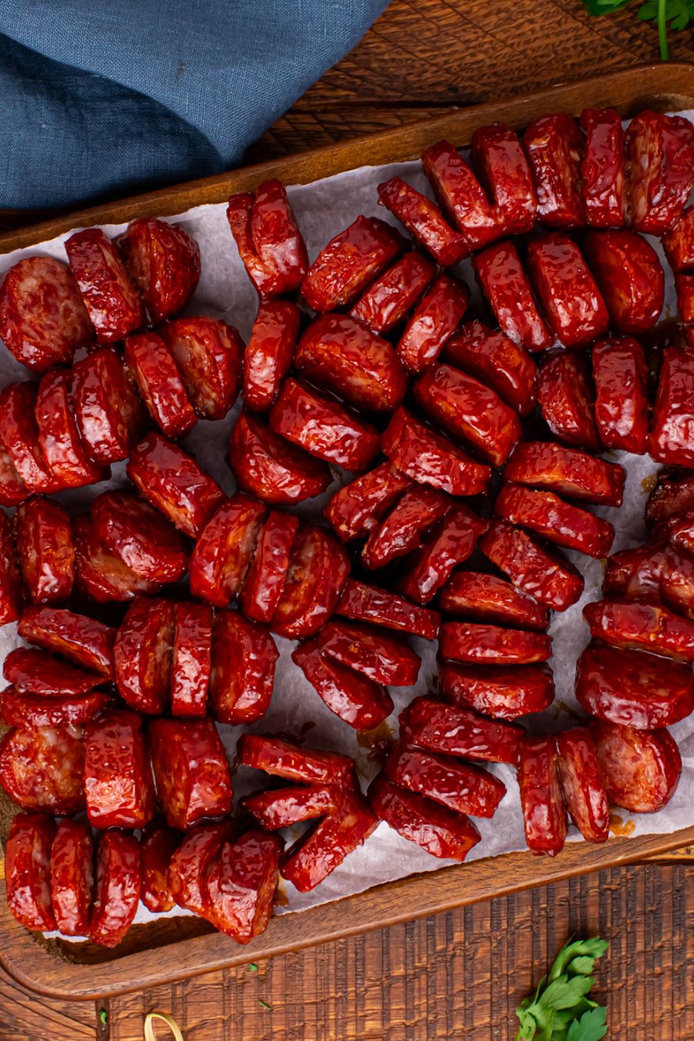 BBQ Hasselback Smoked Sausages on a tray with a blue towel to the side 