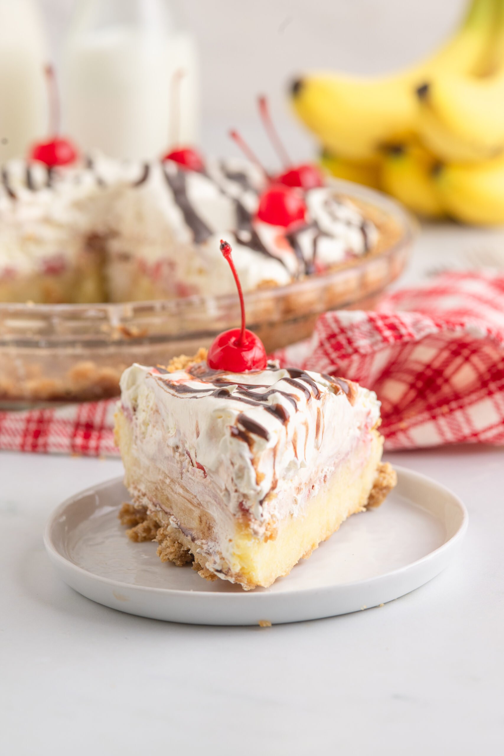 No Bake Banana Split Pie  on a white plate with the whole pie in the background