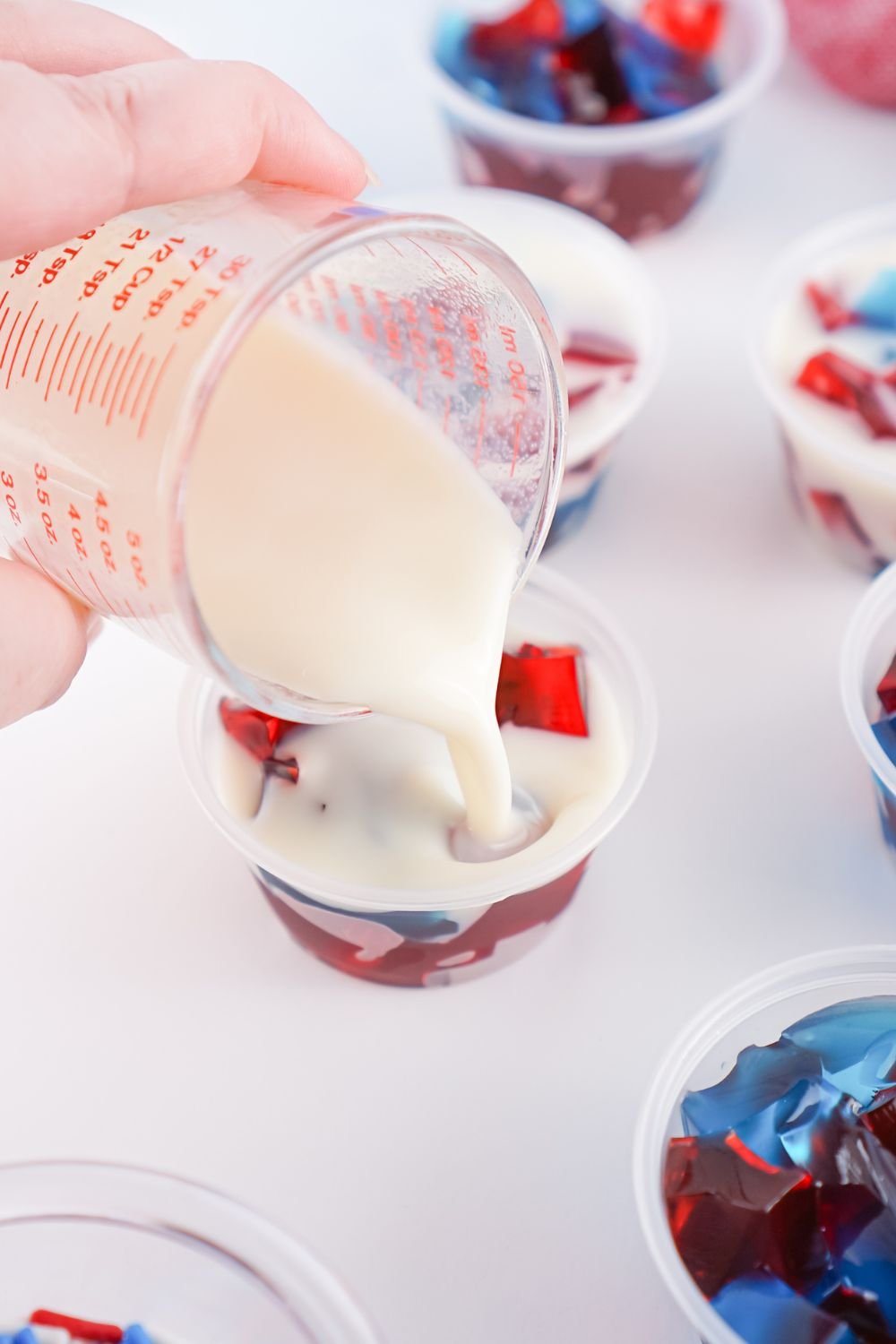 white jello mixture being poured into jello cubes in container 