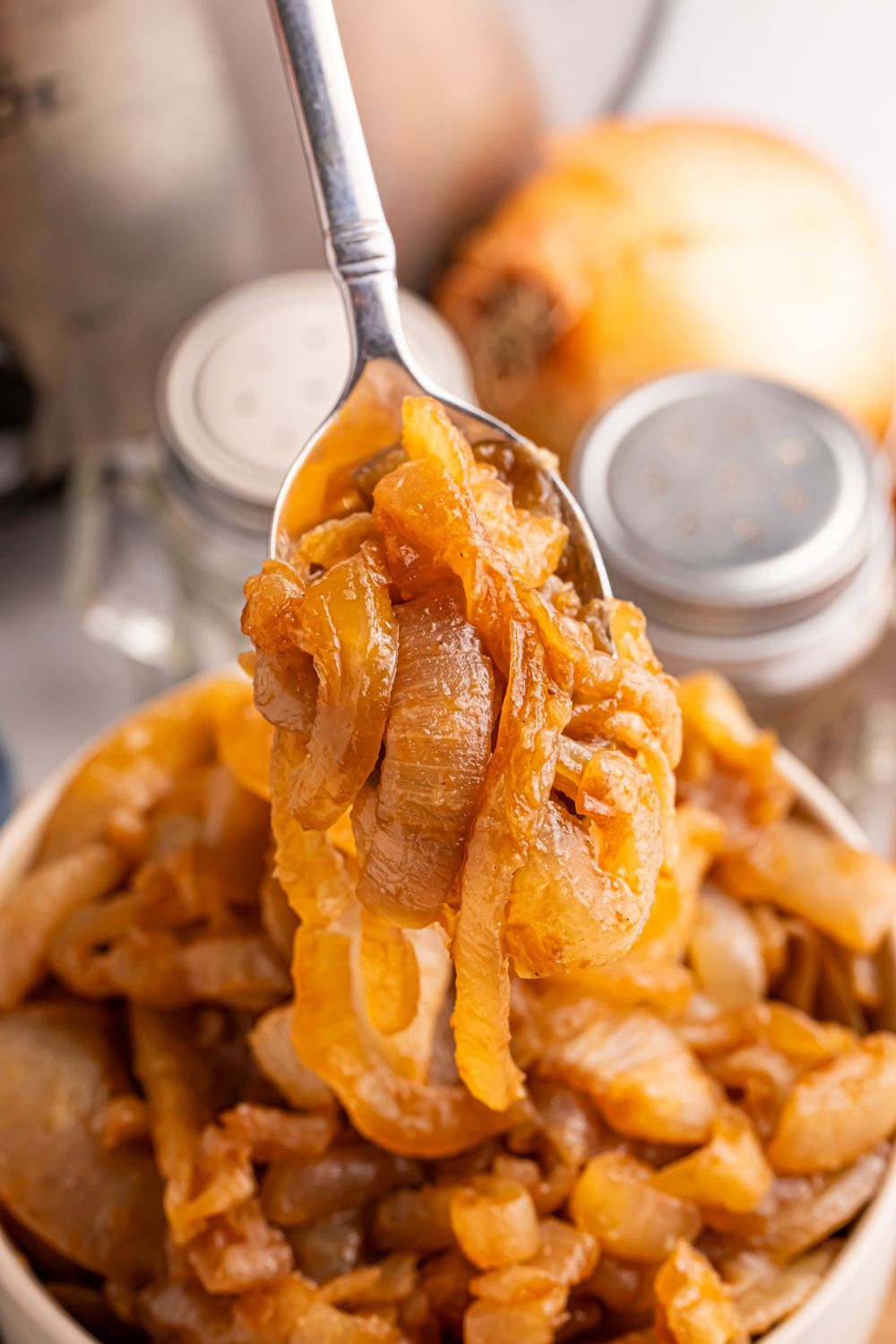 CrockPot Caramelized Onions in a bowl with a spoon lifting some onions out of the bowl