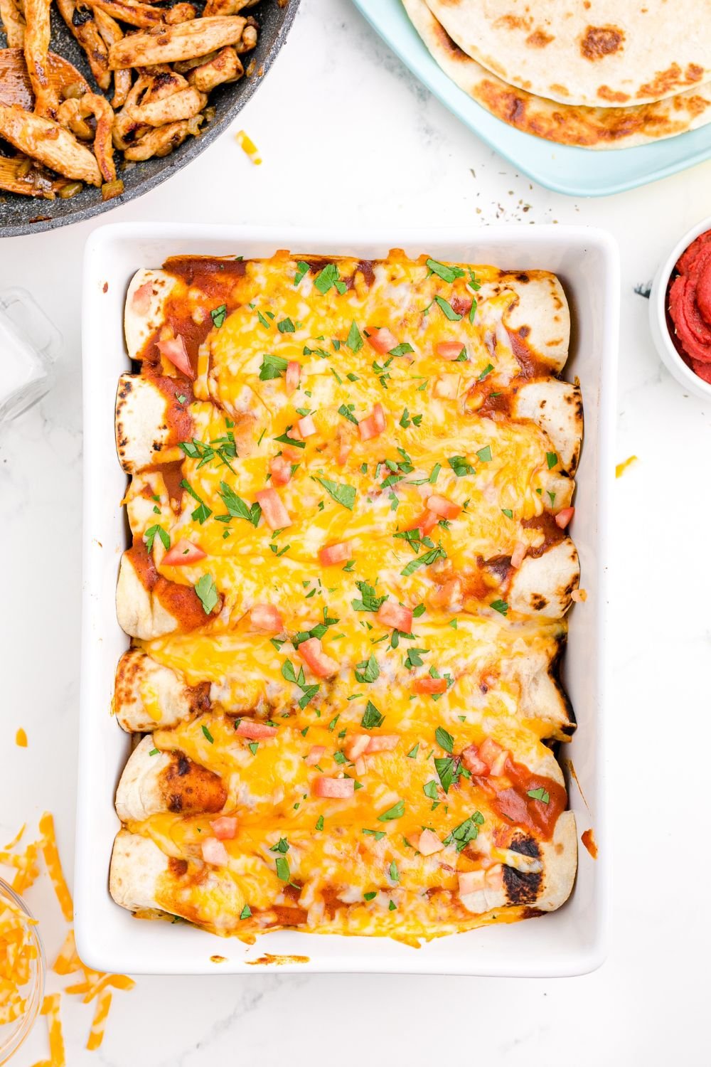 cooked Cheesy Chicken Enchiladas in a casserole pan sitting on table 