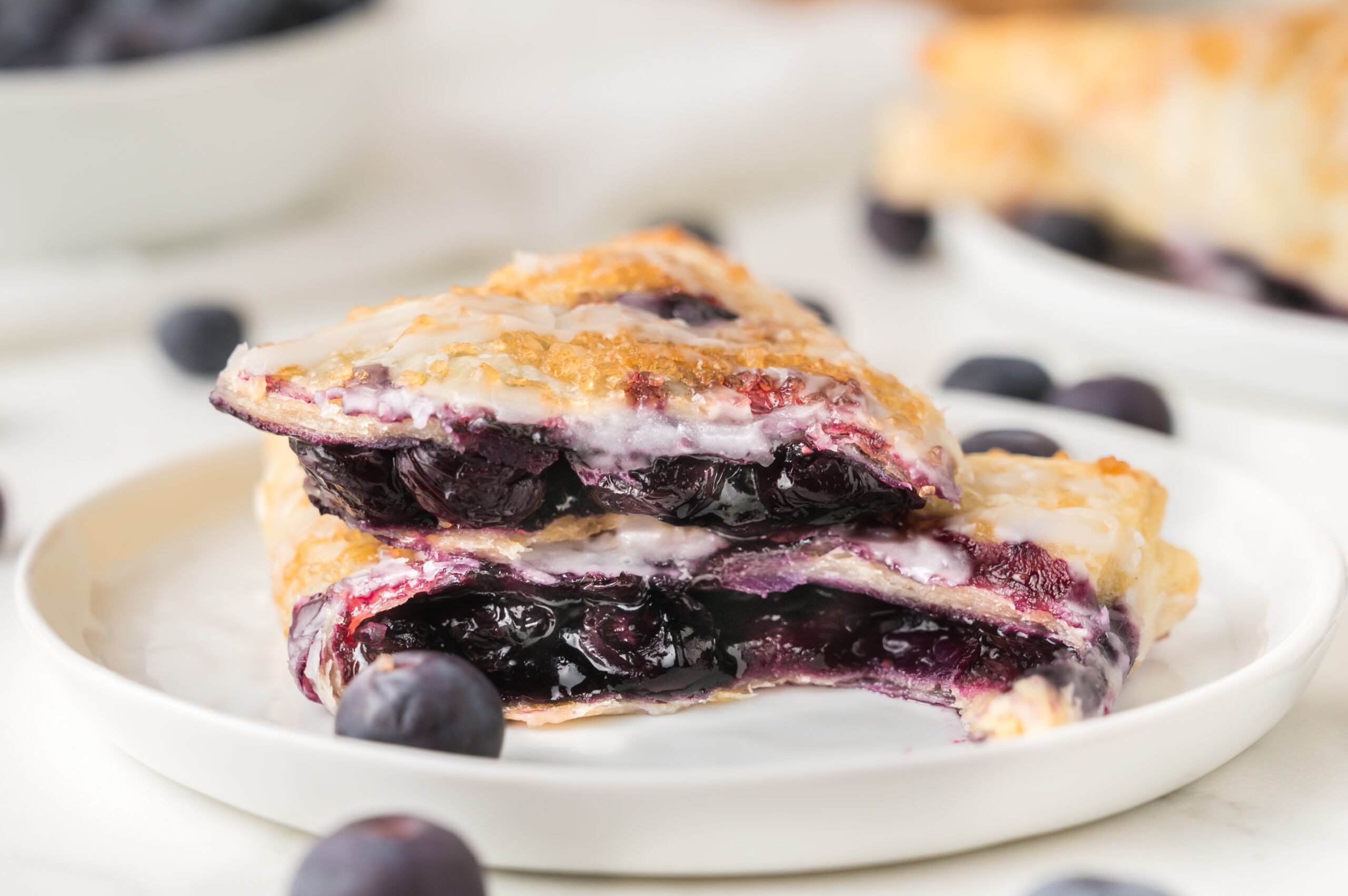 Blueberry Turnovers on plate with fresh blueberries around them on the plate 