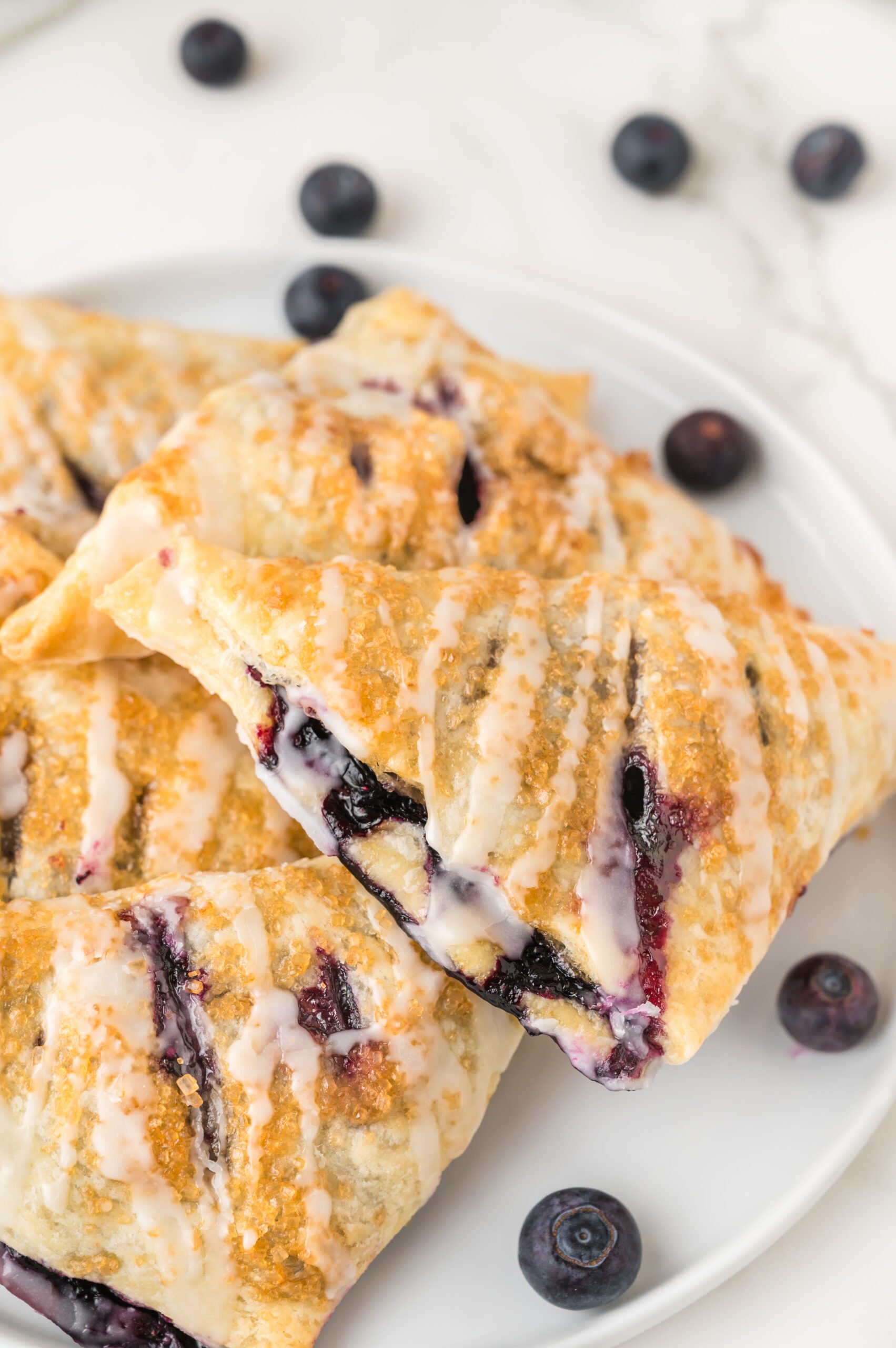 Blueberry Turnovers on plate with fresh blueberries around them on the plate