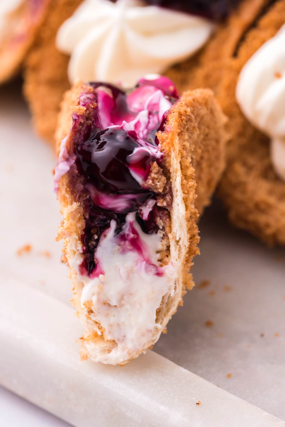 Close up shot of a bite removed from the cheesecake tacos showing the filling. 