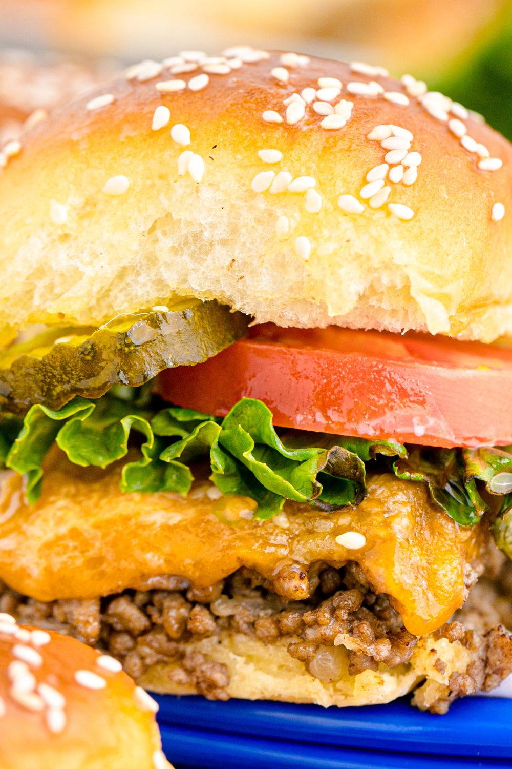 close up of Classic Cheeseburger Slider with tomato, lettuce and pickle on top 
