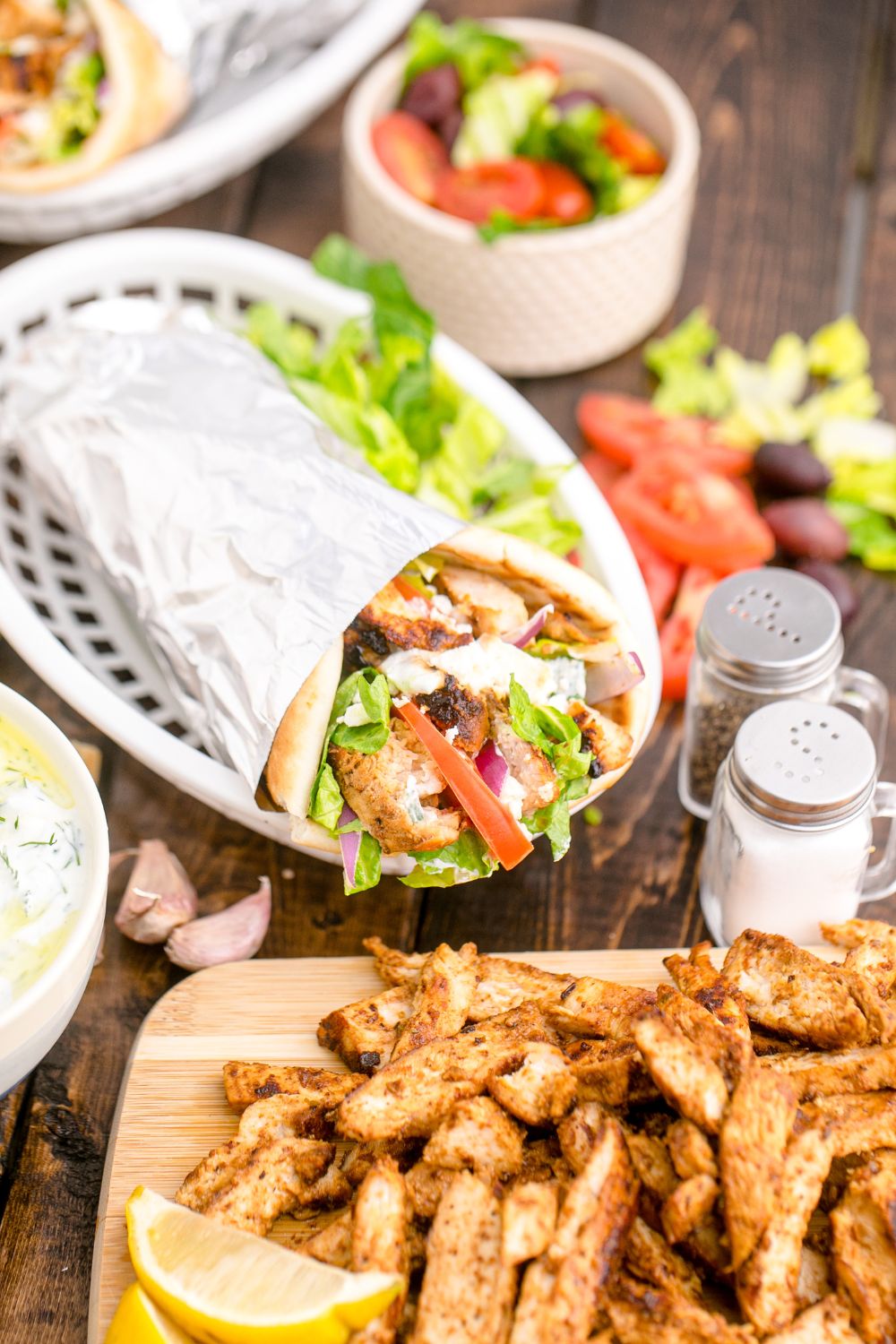 Chicken Gyro wrap in a basket with a cutting board with chicken in front of it 