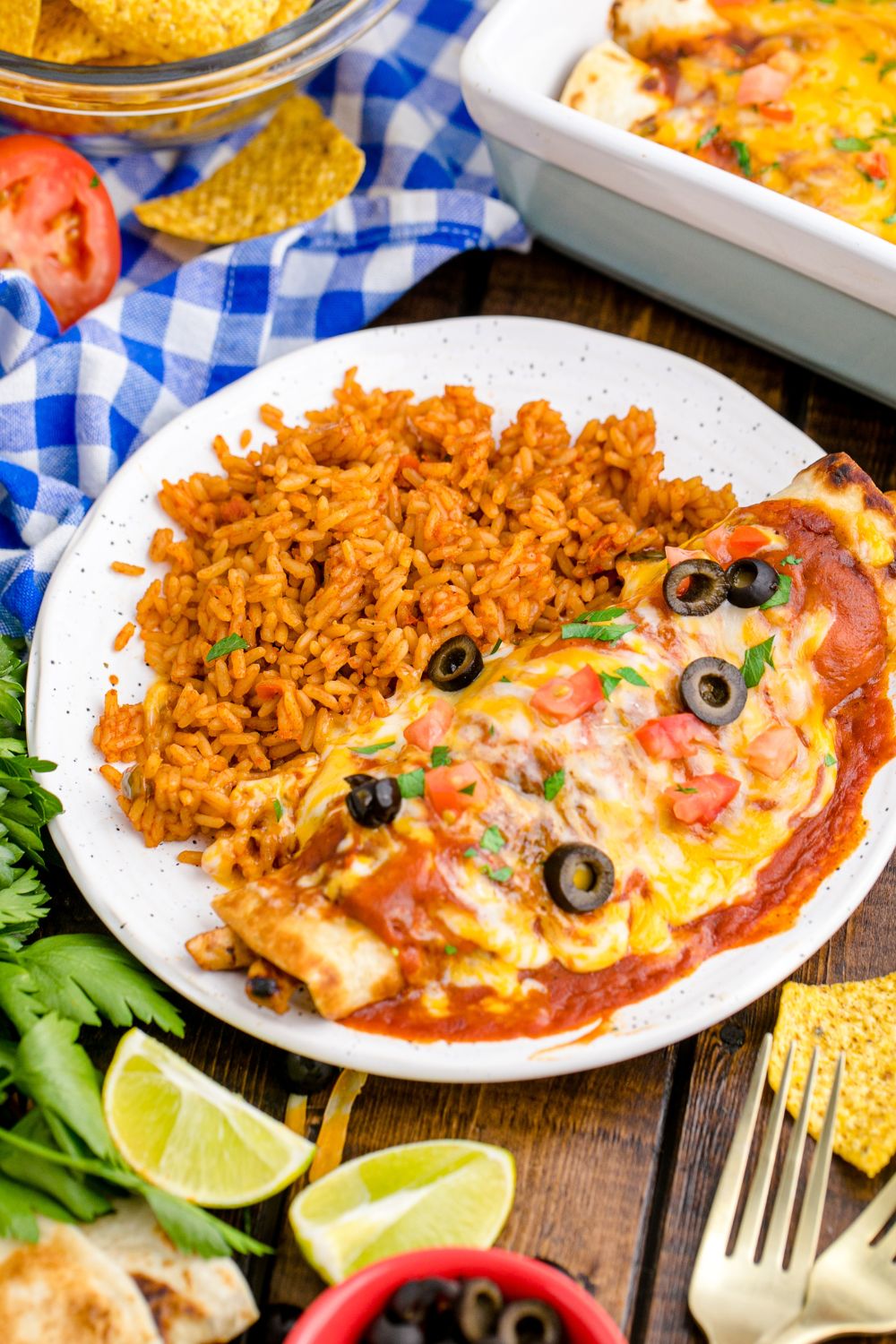 Cheesy Chicken Enchilada on a plate with rice and a blue towel on table behind the plate 