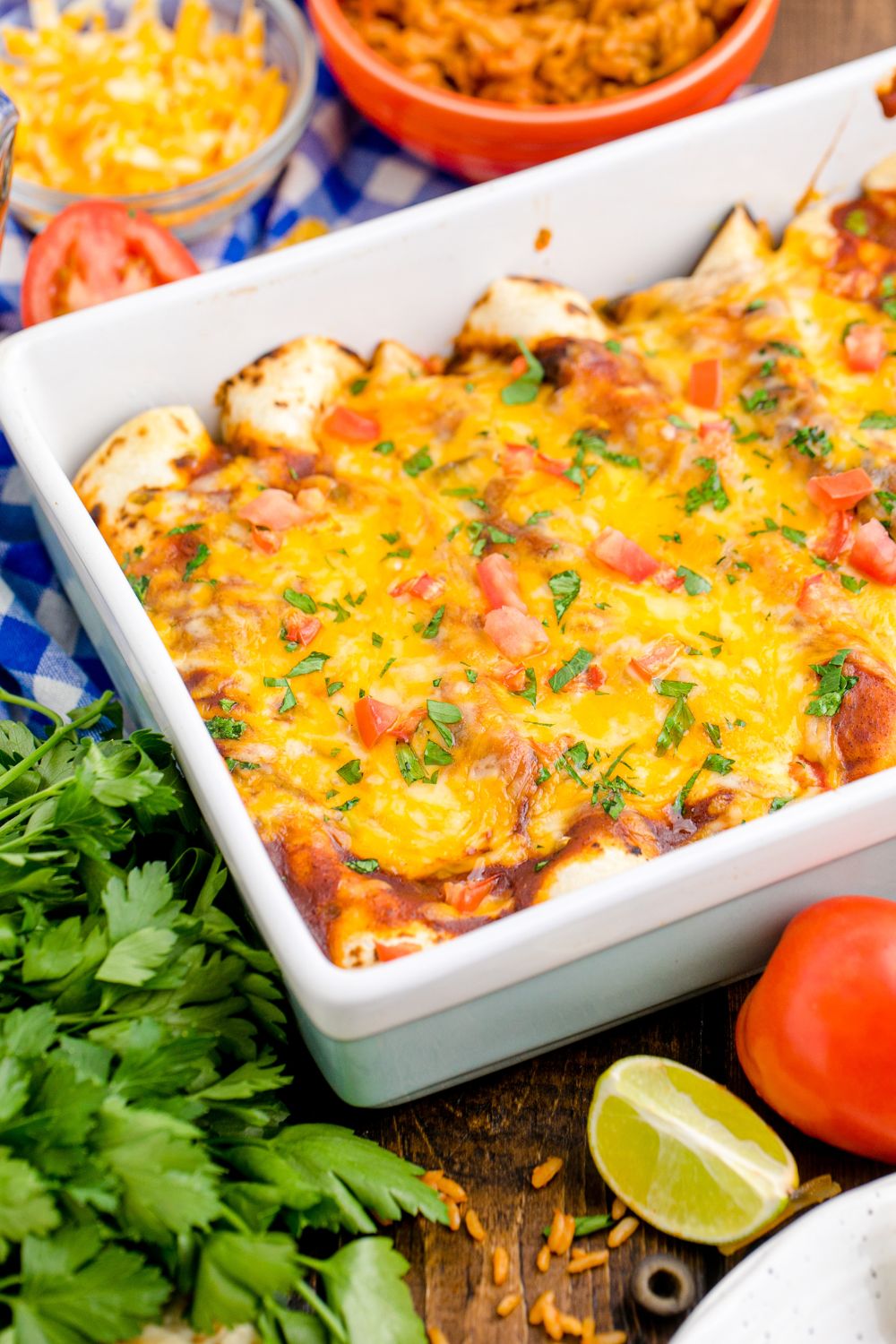 Cheesy Chicken Enchiladas in a casserole dish topped with cilantro and tomatoes 
