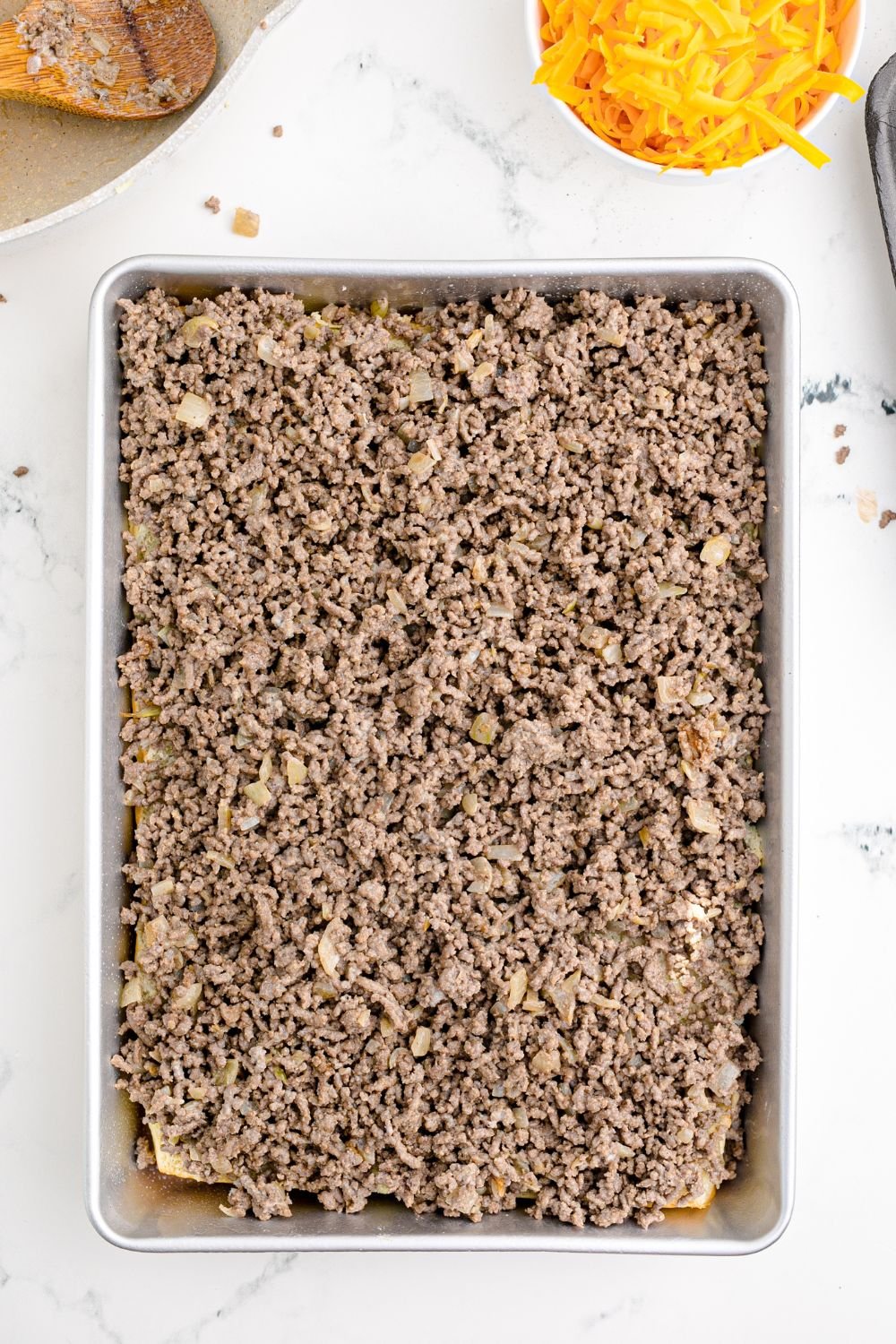 ground beef on top of slider buns in a baking tray
