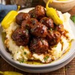 Crockpot Mississippi Meatballs on a plate with a bed of mashed potatoes underneath