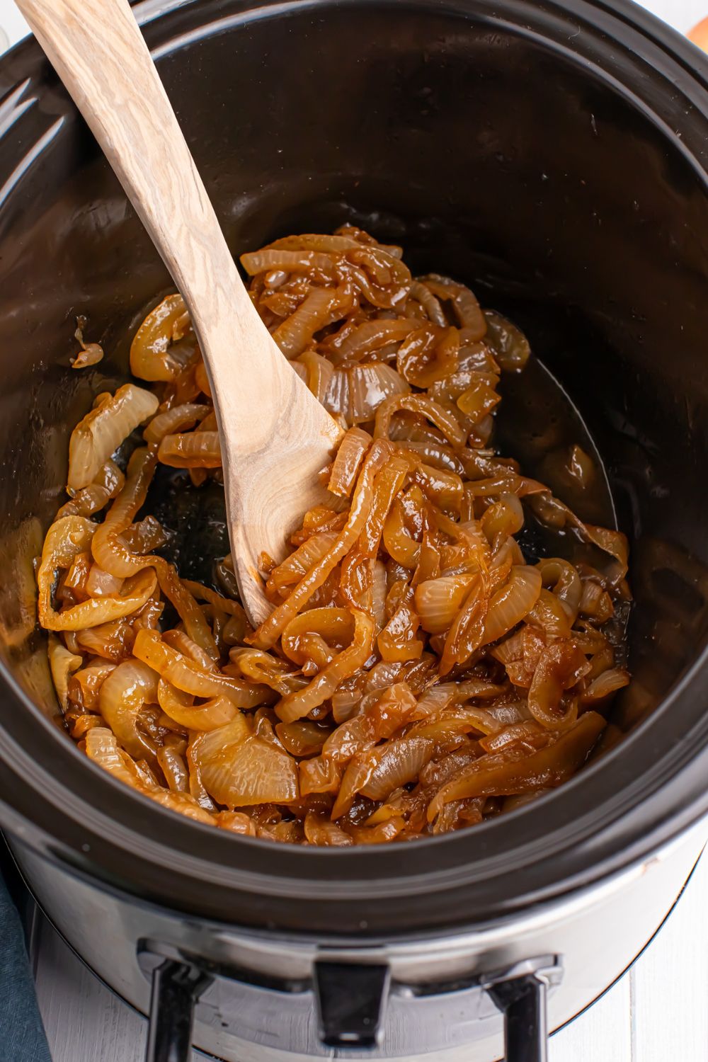 overhead look of CrockPot caramelized onions with a wooden spoon in container