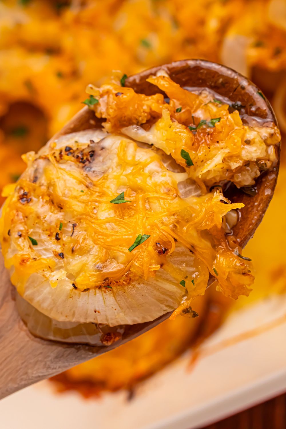 wooden spoon with baked onion and cheese on table