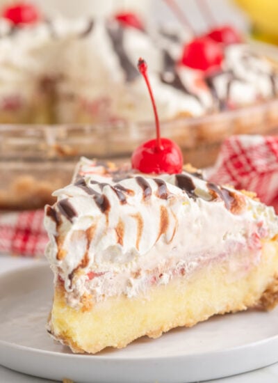 No Bake Banana Split Pie slice on a white plate with the whole pie in the background