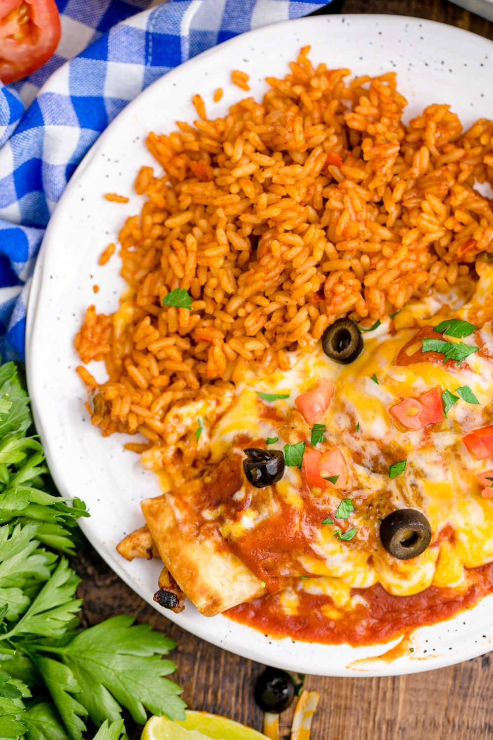 side view of plate that has an enchilada on it and some Mexican rice with cilantro bundle to the side of plate 