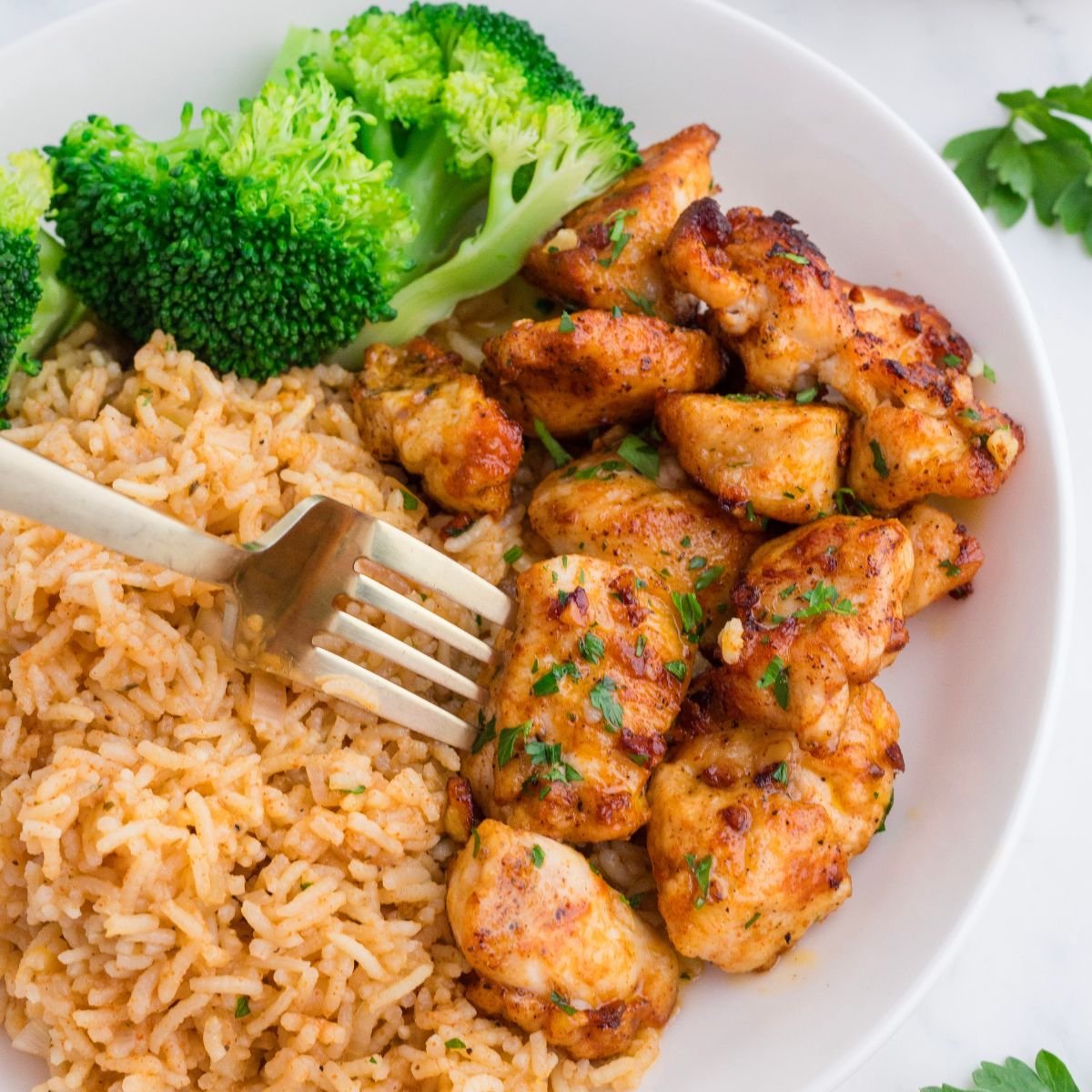 Garlic Butter Chicken Bites on plate with rice and broccoli on side of it