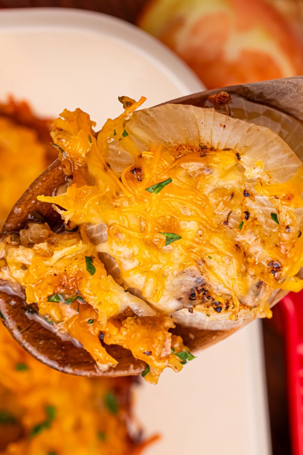 Cheesy Tennessee Onions being lifted out of a pan with a wooden spoon 