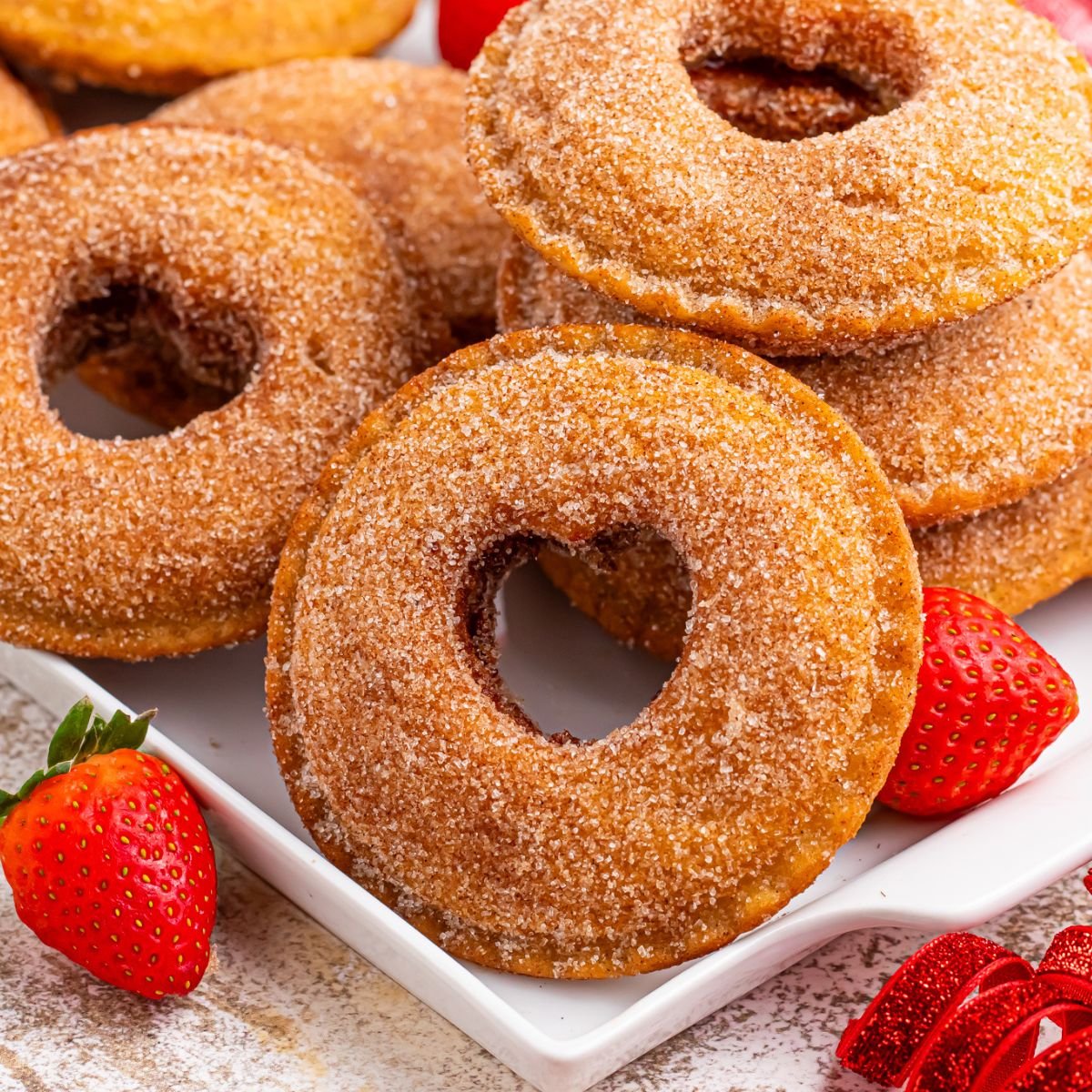 plate with Fried Strawberry Uncrustables that have been fried and rolled in sugar on plate with strawberries in front of plate 