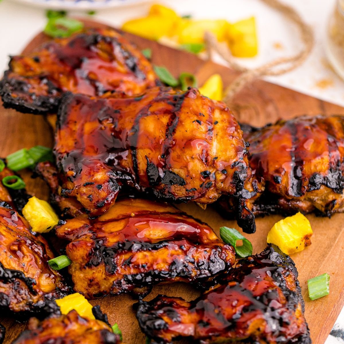 Huli Huli Chicken on a cutting board with pineapple on table 