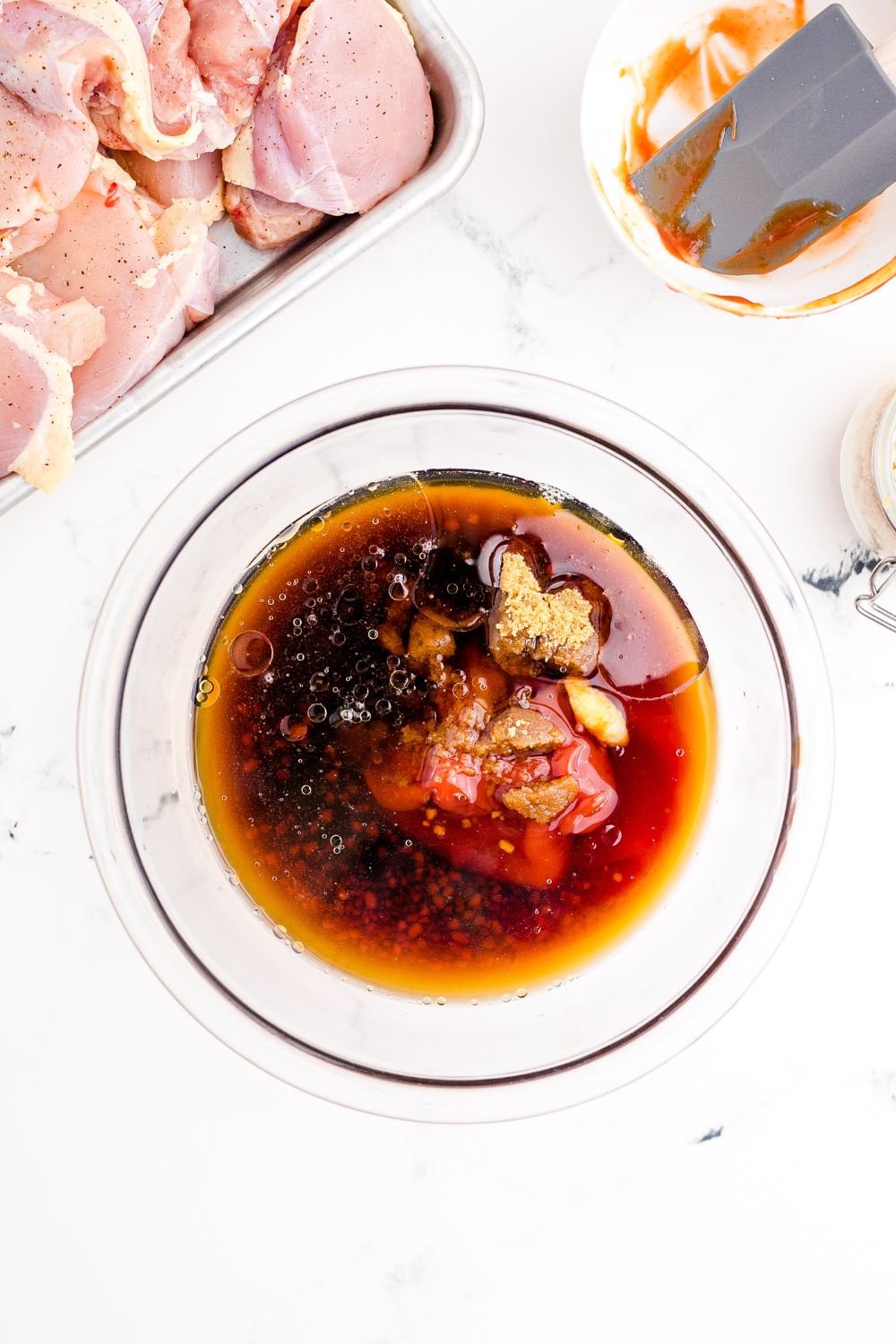 Huli Huli Chicken marinade in a bowl with raw chicken to the side 