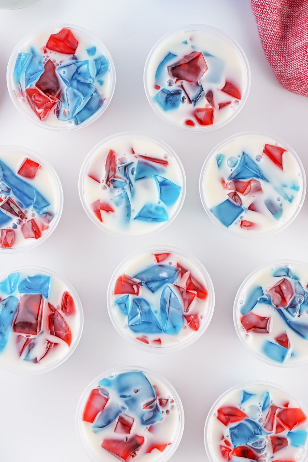 Red White and Blue Jello Shots in containers spread out on table 