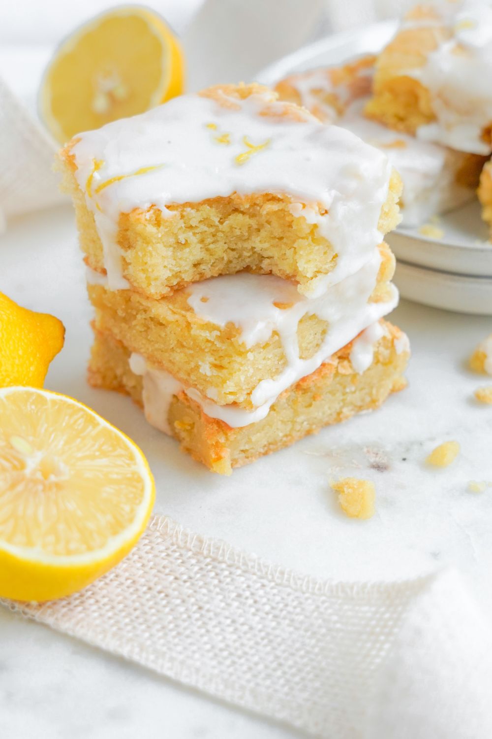 Lemon Sugar Cookie Bars stacked on top of one another with top bar having a bite taken out of it