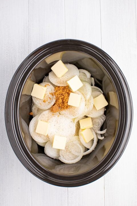 onions, brown sugar, butter and seasonings in a CrockPot on table for making Crockpot caramelized onions 