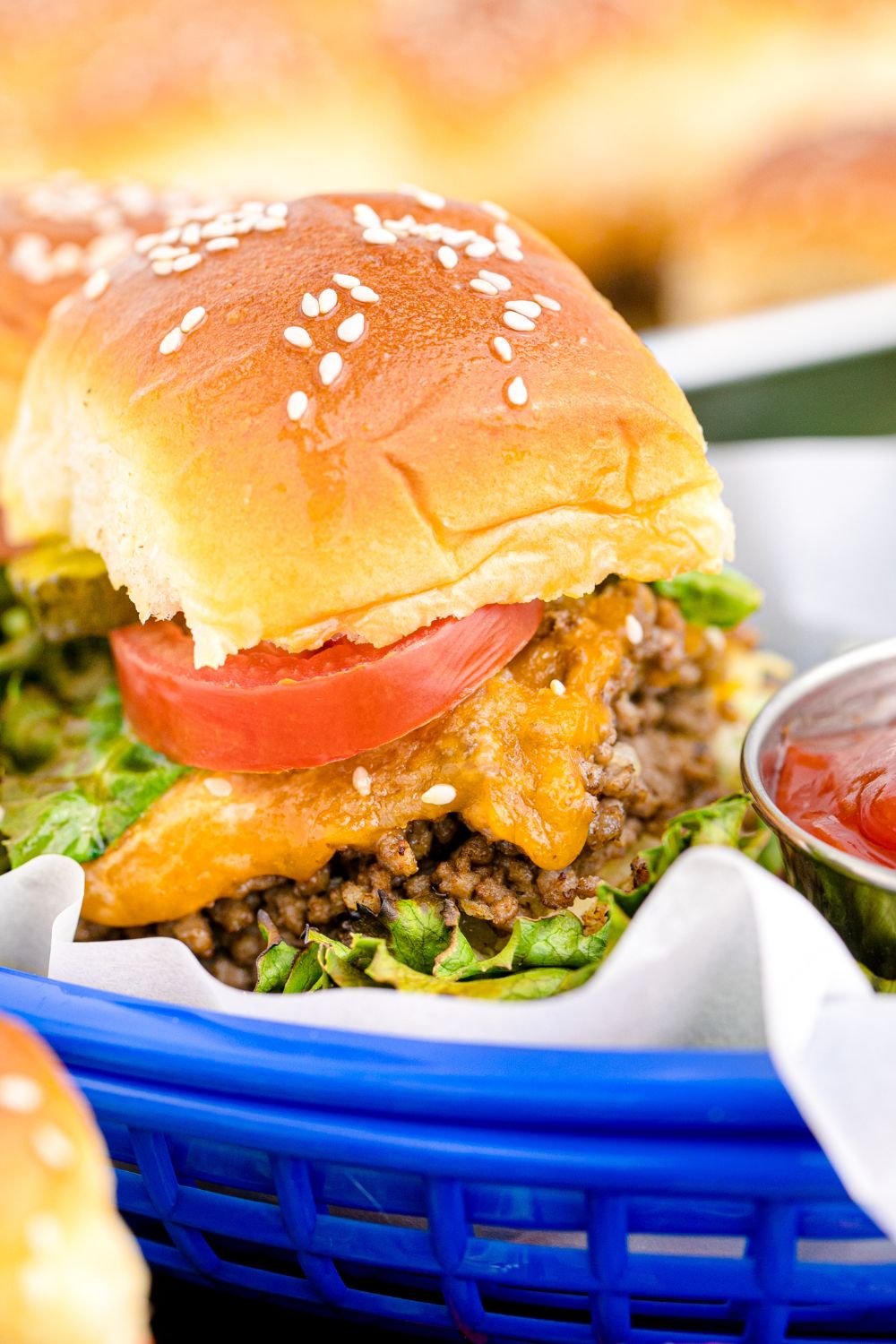 Classic Cheeseburger Slider in a basket with a small bowl of ketchup to the side of burger 