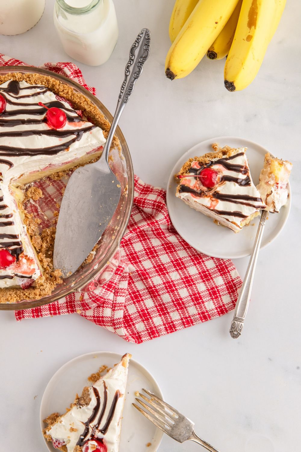 No Bake Banana Split Pie on table with a few slices placed on plates 