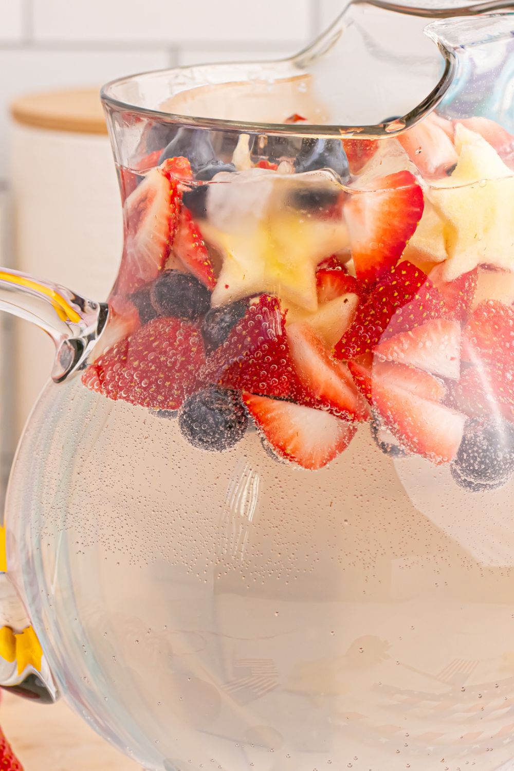 close up view of Patriotic Sparkling Lemonade in pitcher, with a mix of fruit on top of pitcher to add color 