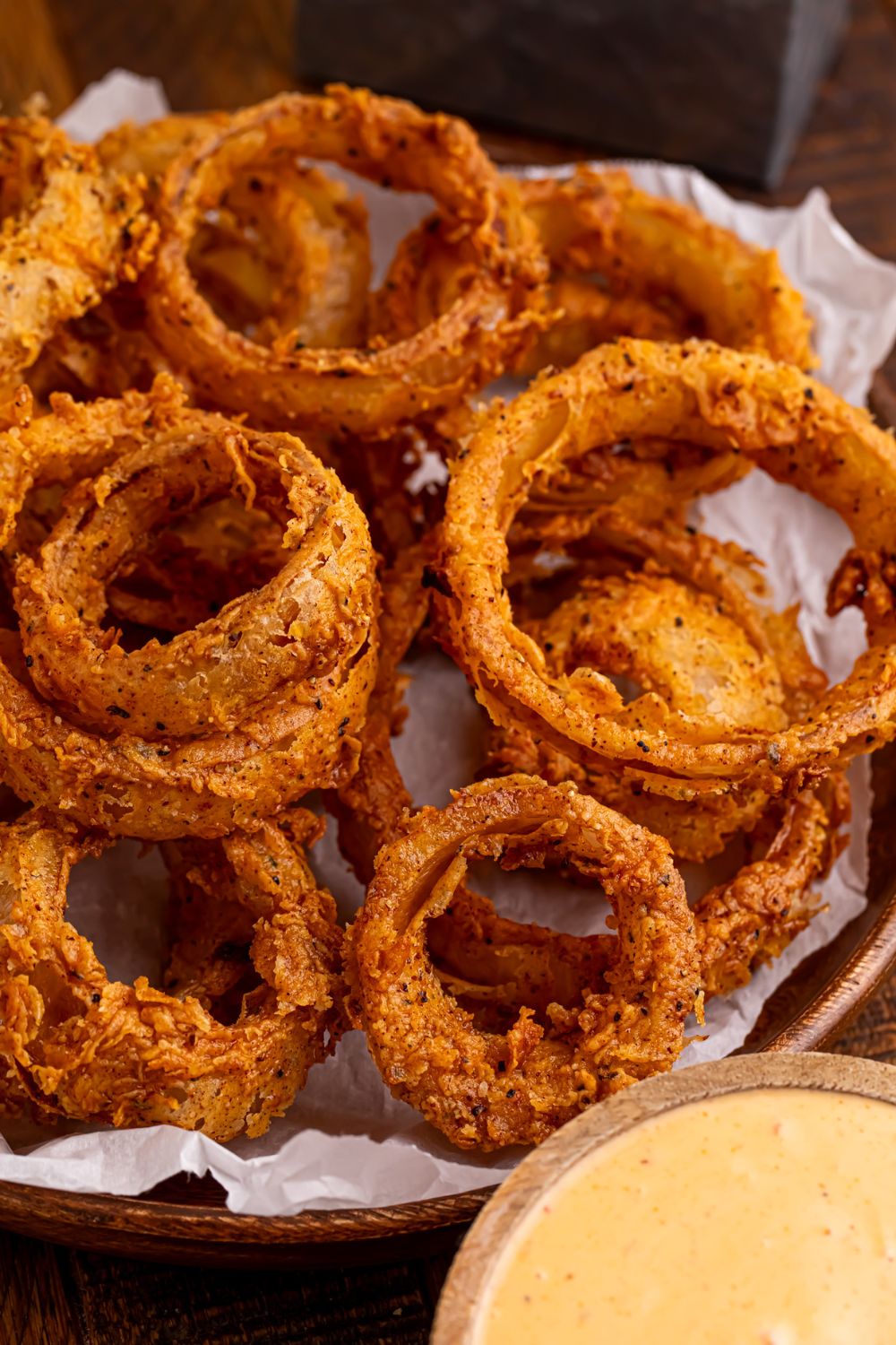 Homemade Deep Fried Onion Rings in a bowl with a bowl of dip to the side 