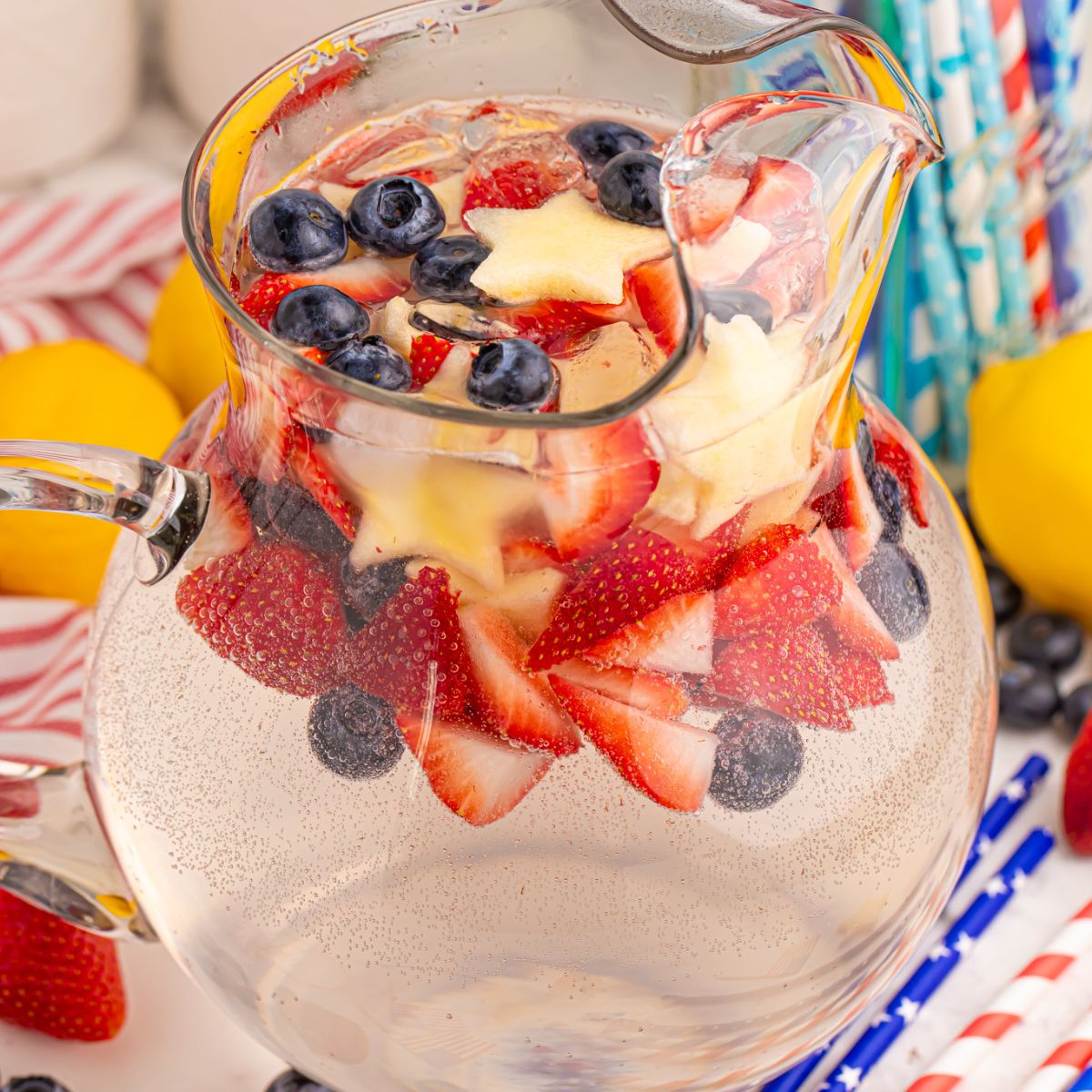 Patriotic Sparkling Lemonade in a pitcher with red white and blue fruit and ice in pitcher sitting on table