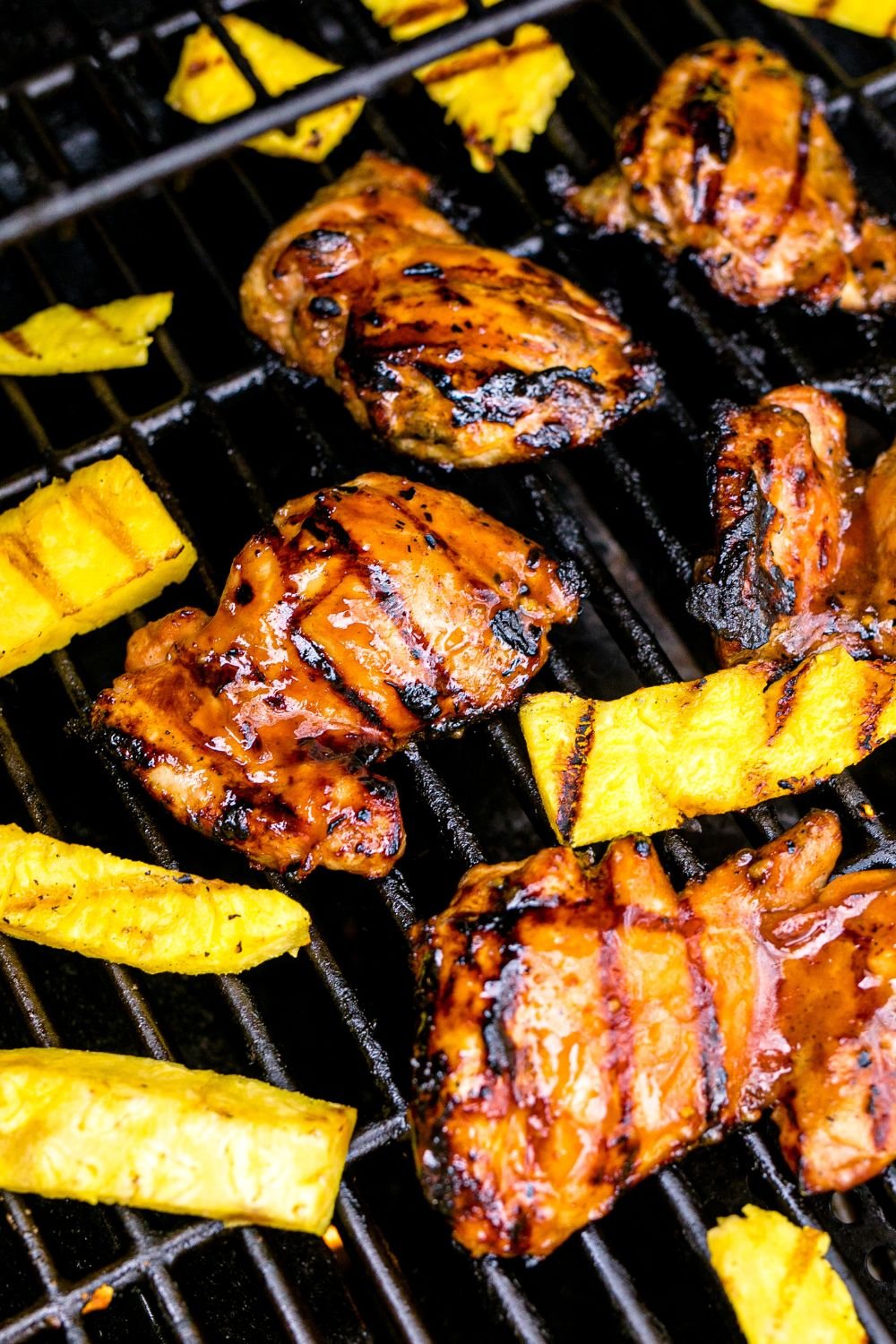 Huli Huli Chicken on grill cooking with sliced pineapple slices 