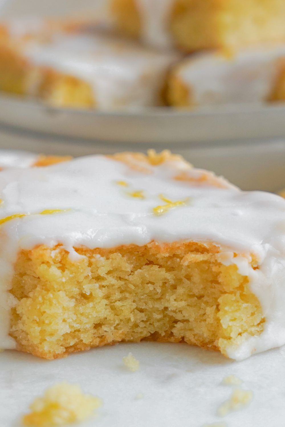 Lemon Sugar Cookie Bar sitting on table with a bite taken out of the bars to show close up of center of bar
