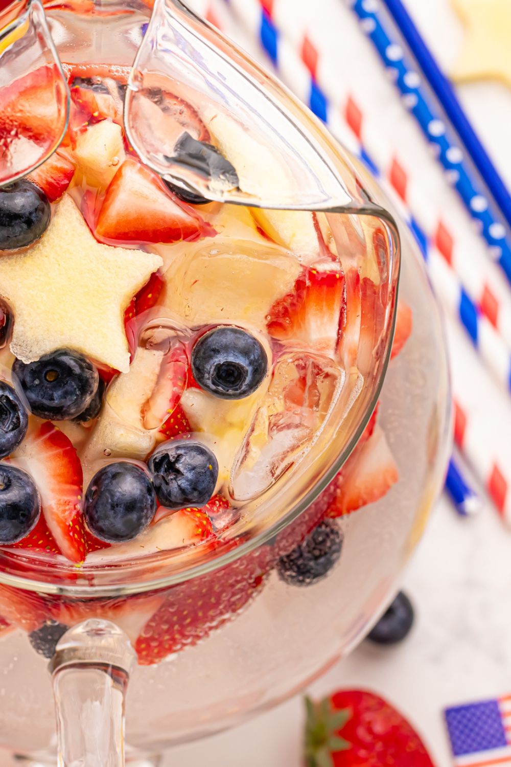 overhead look of pitcher with Patriotic Sparkling Lemonade with red, white and blue straws to side on table 